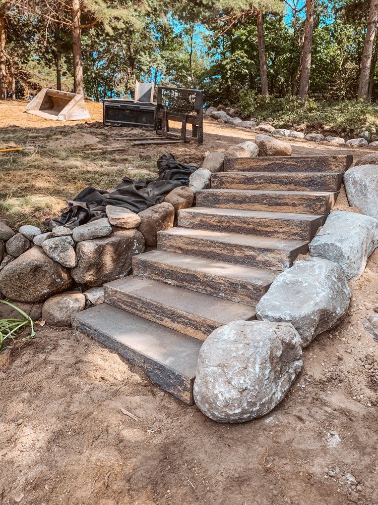 A set of stone stairs surrounded by rocks in a yard.