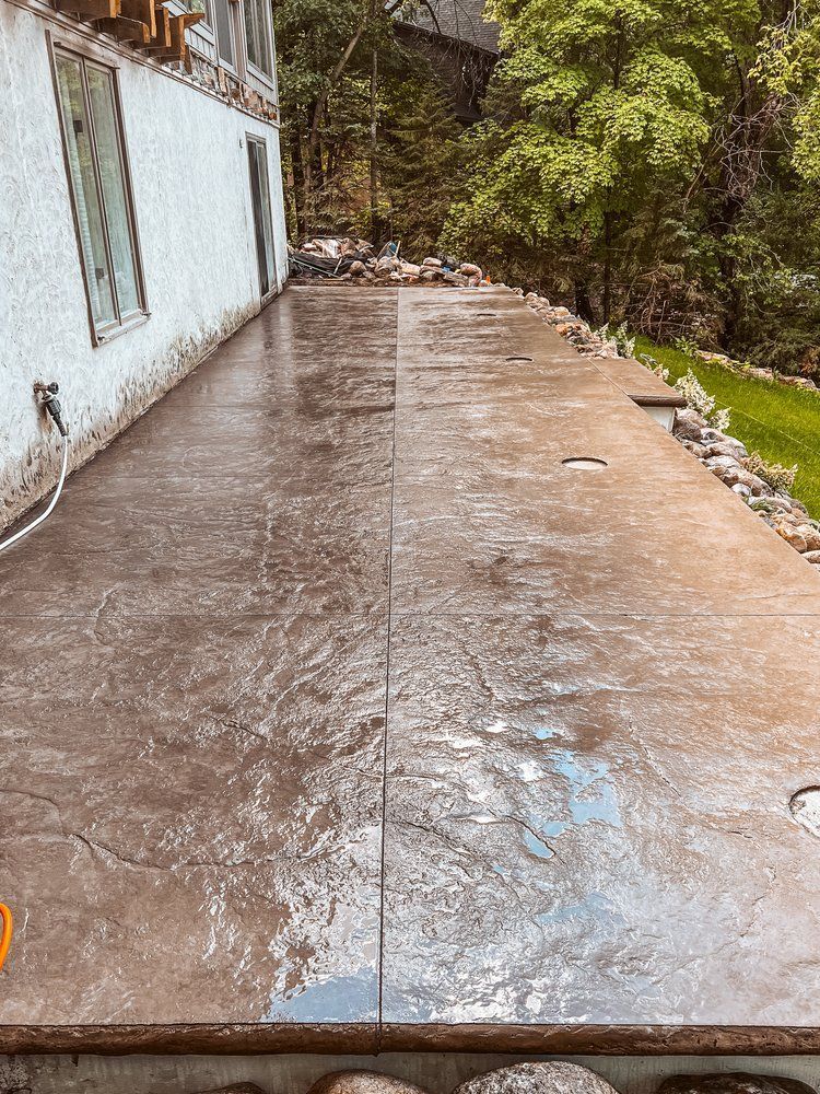 A concrete patio in front of a house with trees in the background.