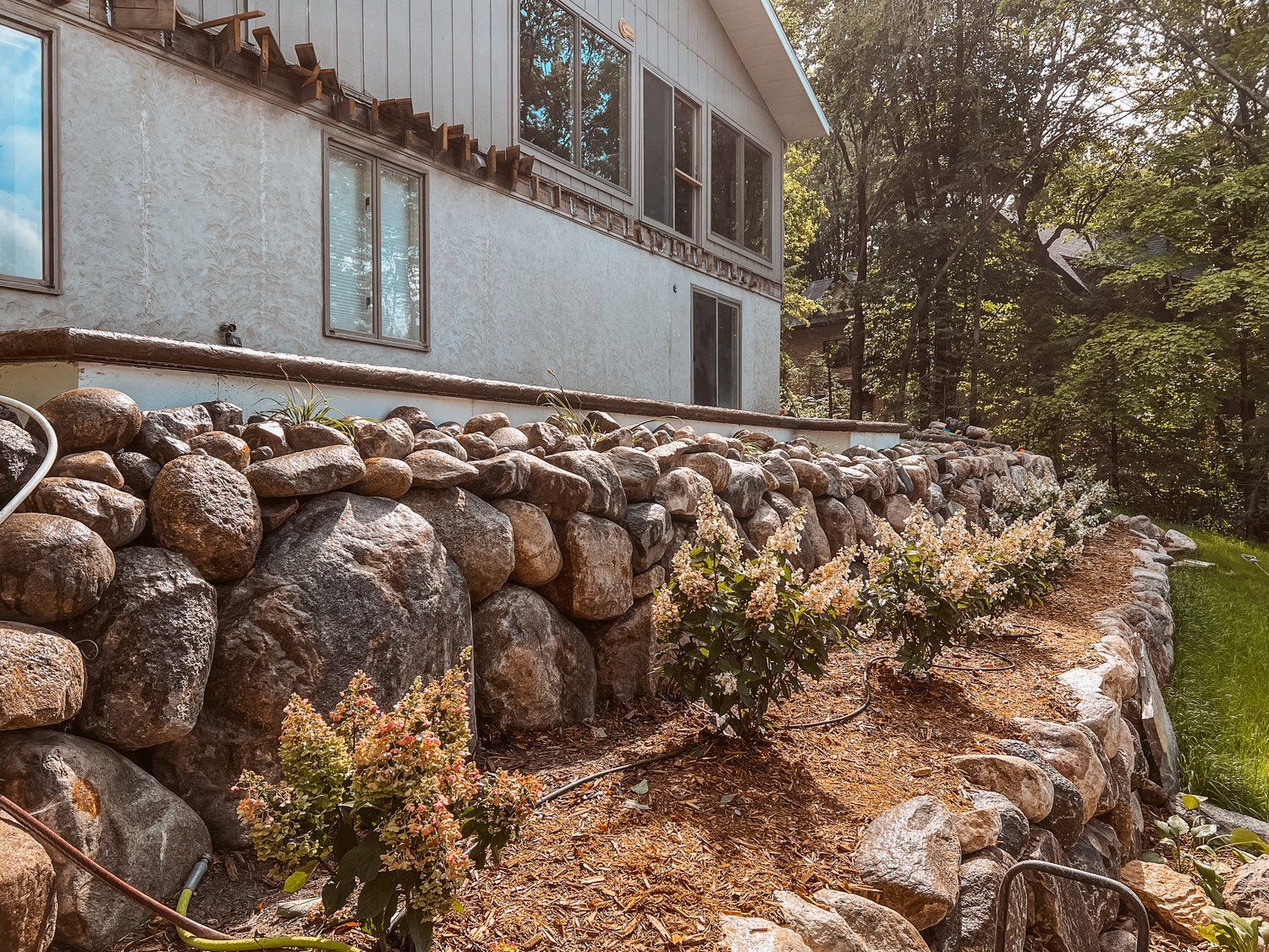 A house with a stone wall in front of it.