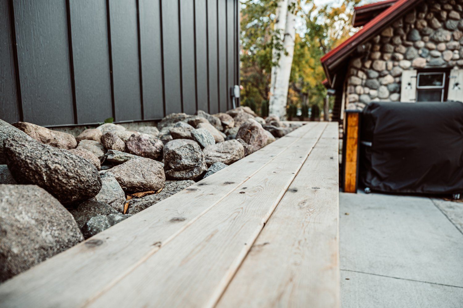 A wooden deck is sitting next to a stone building.