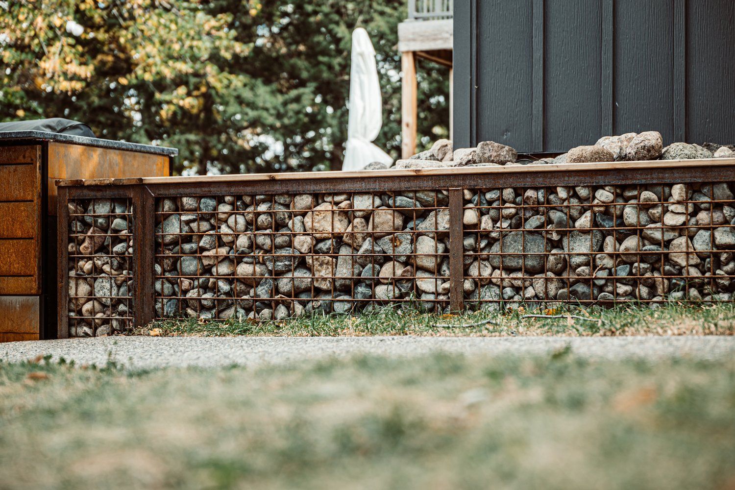 A stone wall with a wooden fence in front of a house.