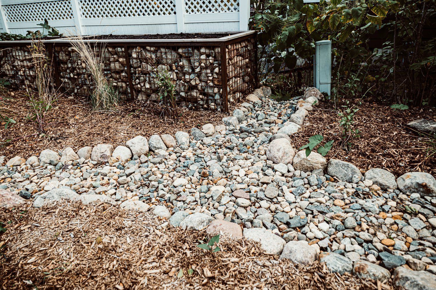 A path made of rocks and mulch in a garden next to a house.