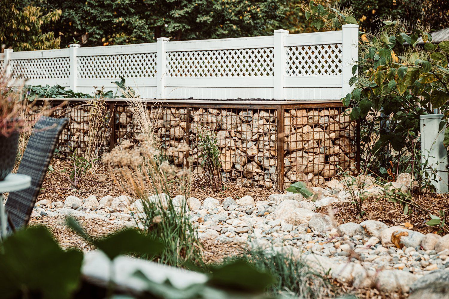 A white fence is surrounded by rocks in a garden.