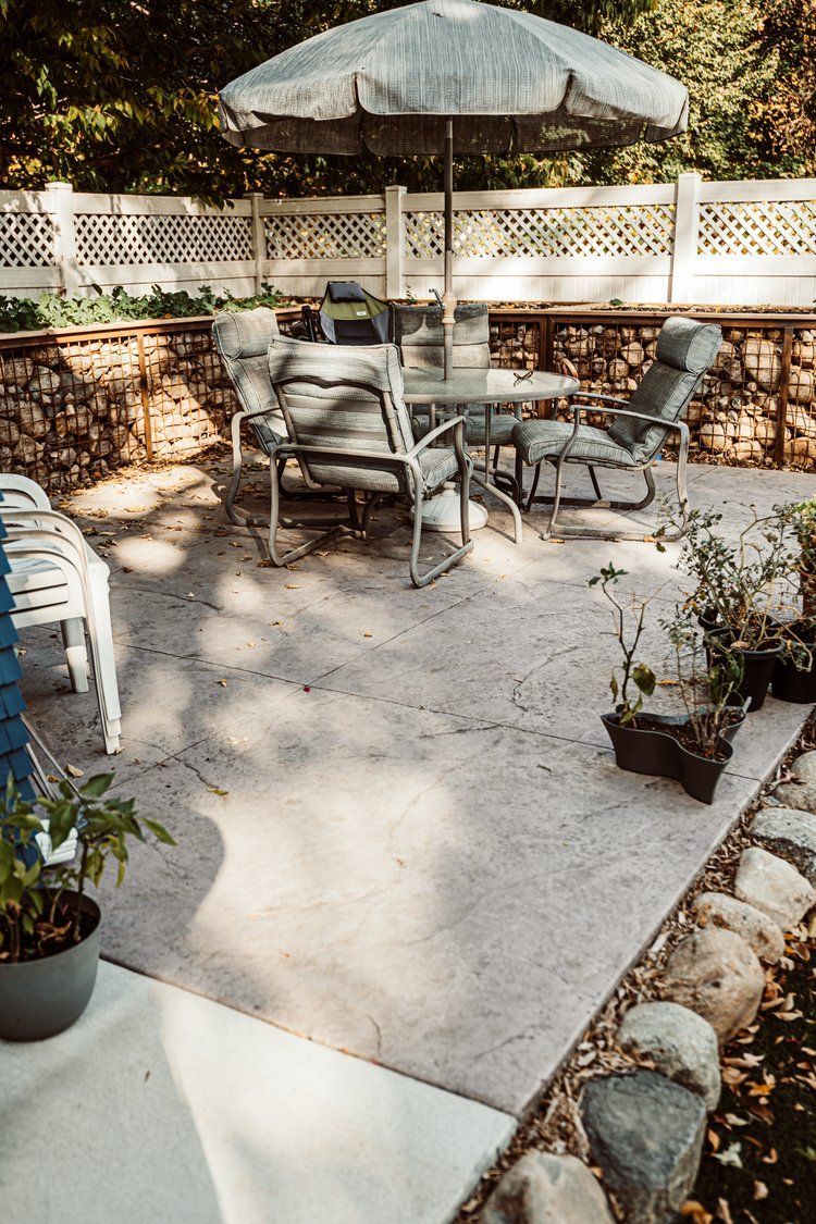 A patio with a table and chairs and an umbrella.