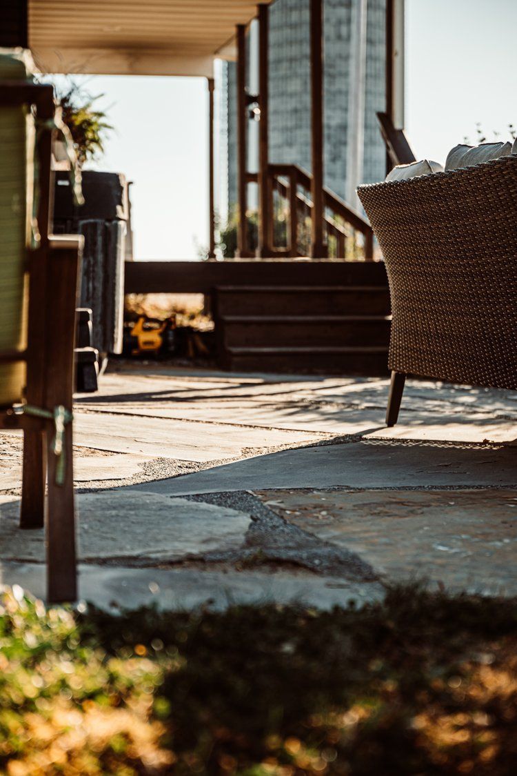 A wicker chair is sitting on a stone patio in front of a house.