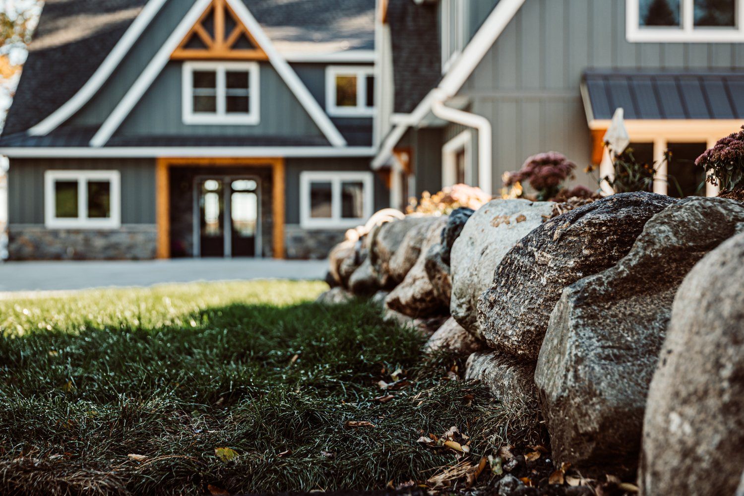 A large house with a stone wall in front of it.
