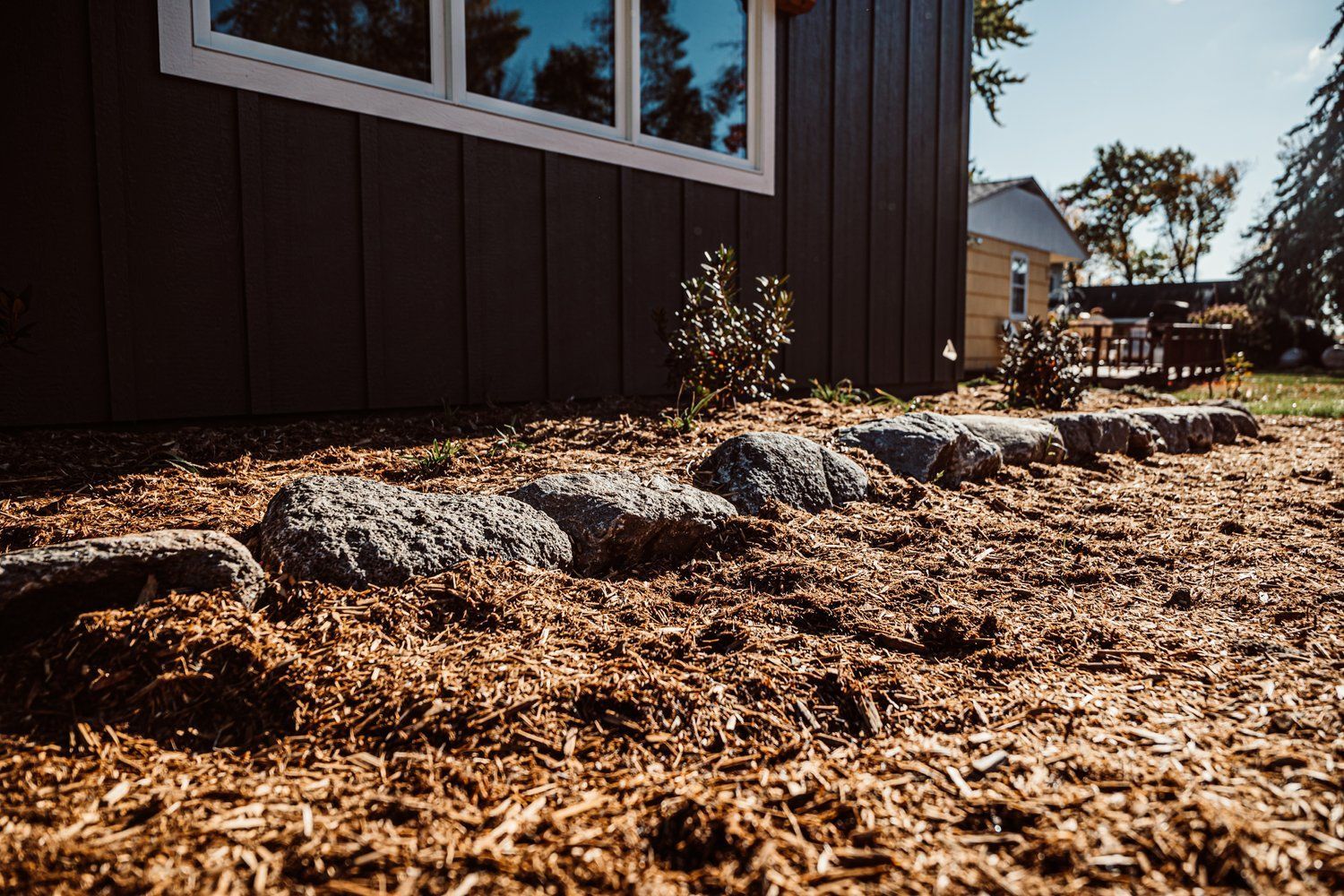 A house with a lot of rocks and mulch in front of it.