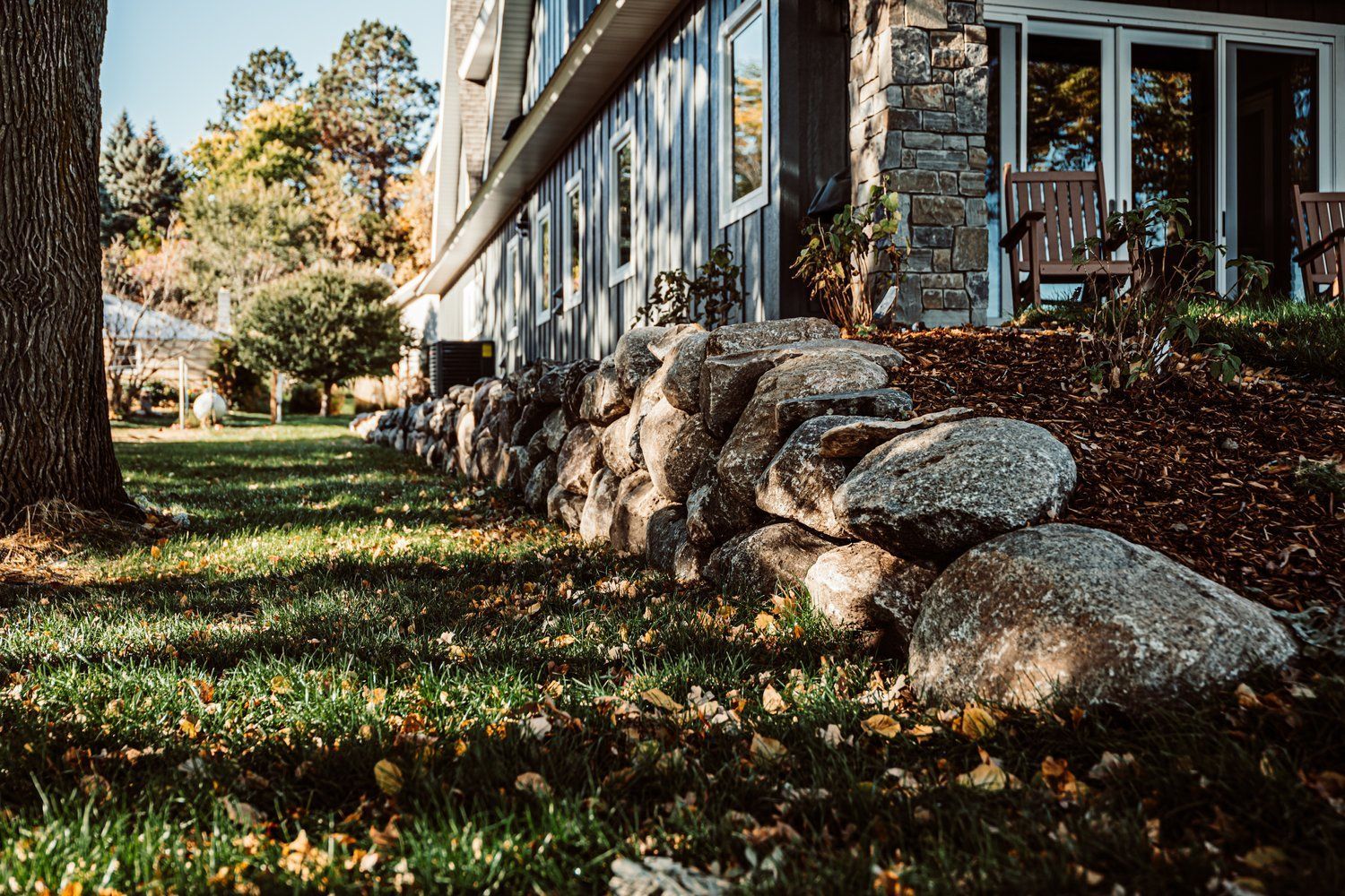 A large rock wall is in front of a house.