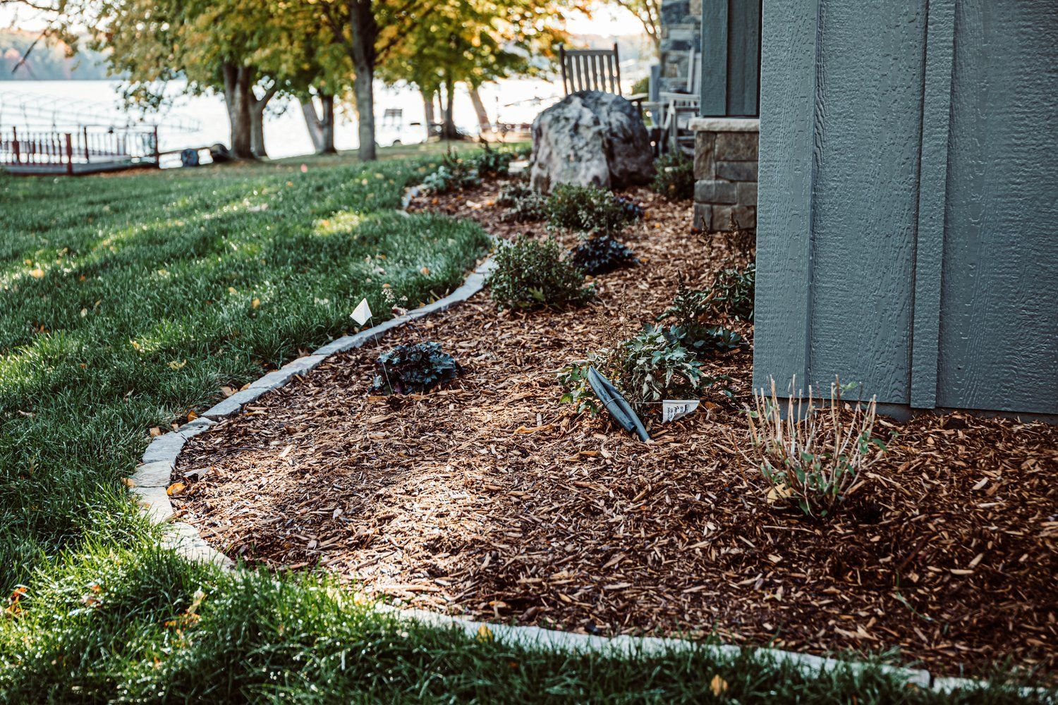 A lawn with a concrete curb and mulch in front of a house.