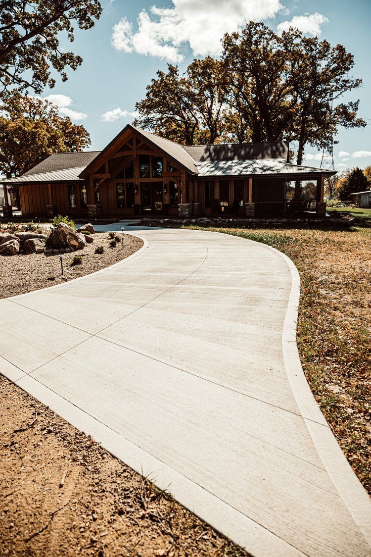 A concrete driveway leading to a large wooden house.