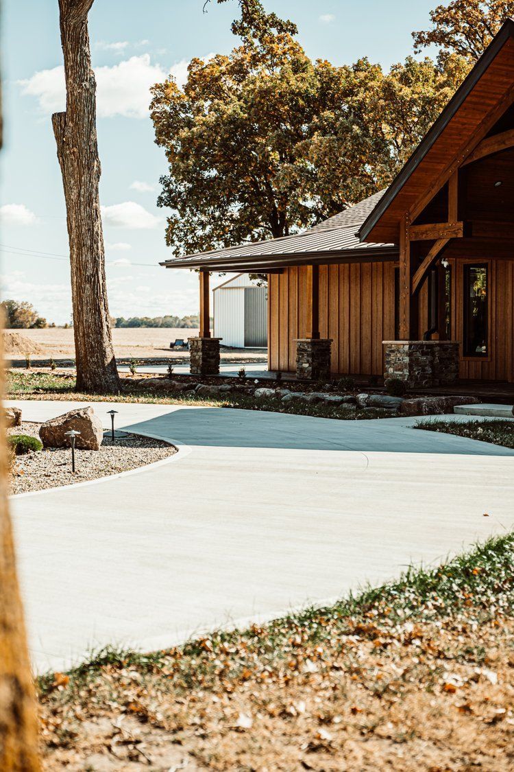 A large wooden house with a concrete driveway in front of it.