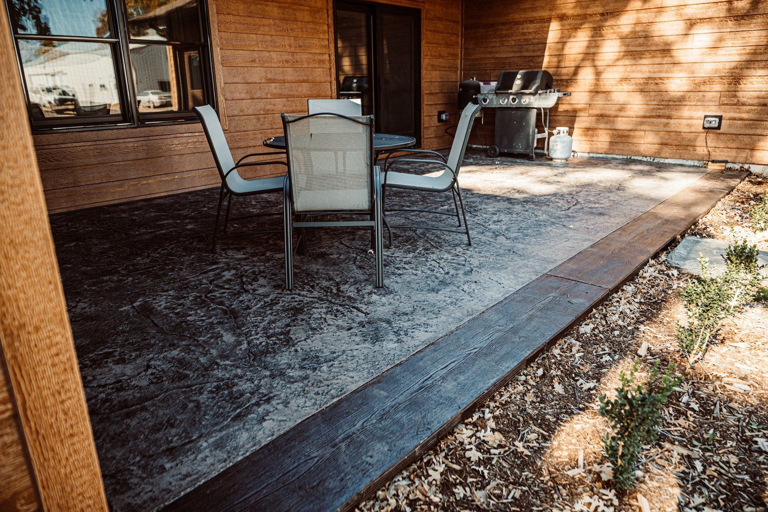 A patio with a table and chairs and a grill.