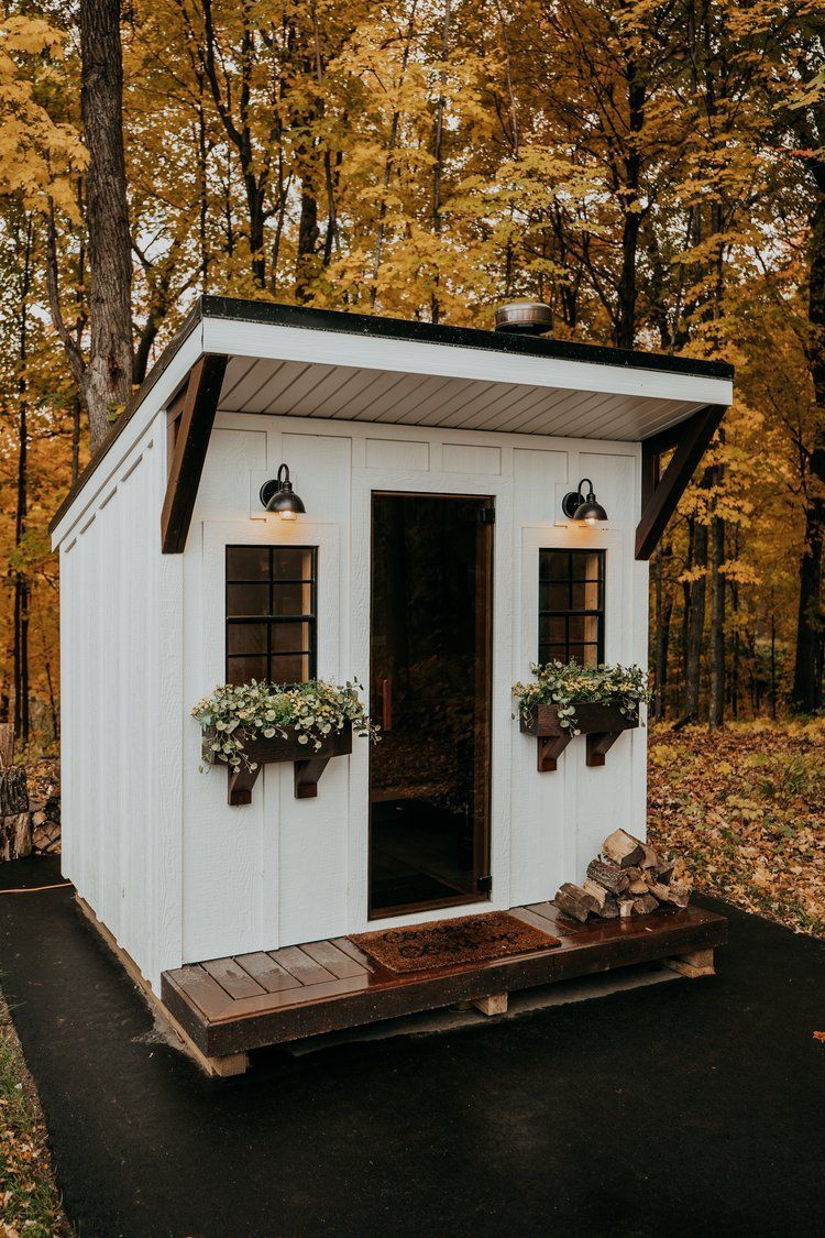 A small white shed is sitting in the middle of a forest.