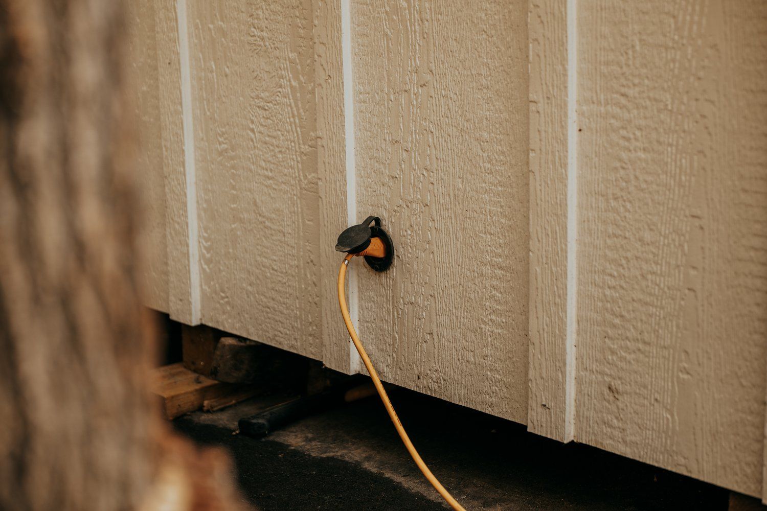 A power cord is plugged into the side of a building.