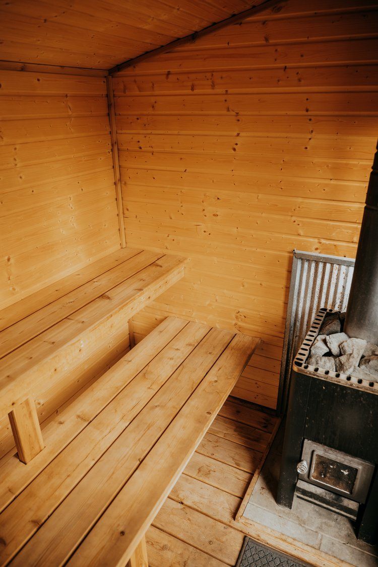 A wooden sauna with a wood stove and benches.