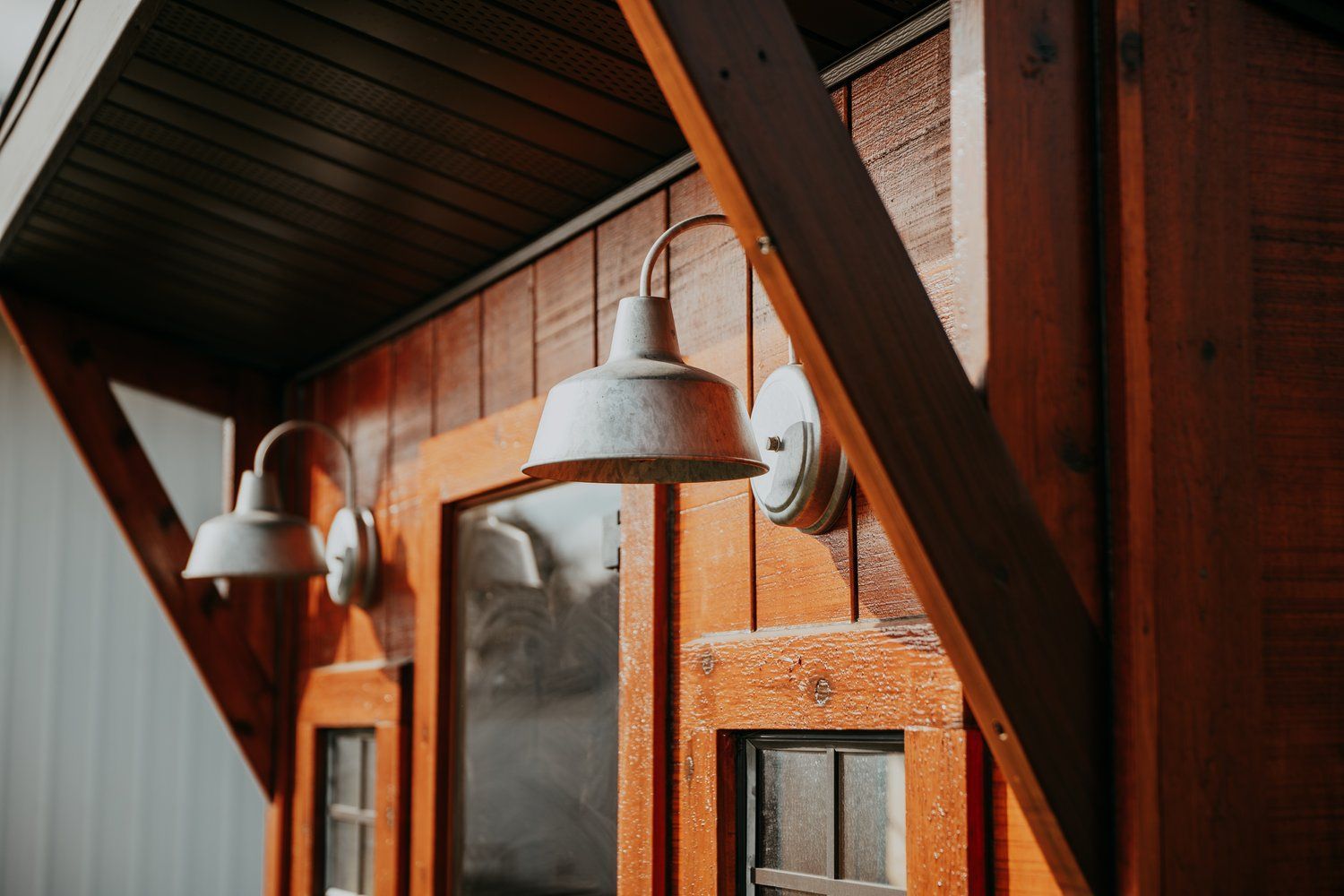There are two lights on the side of a wooden building.