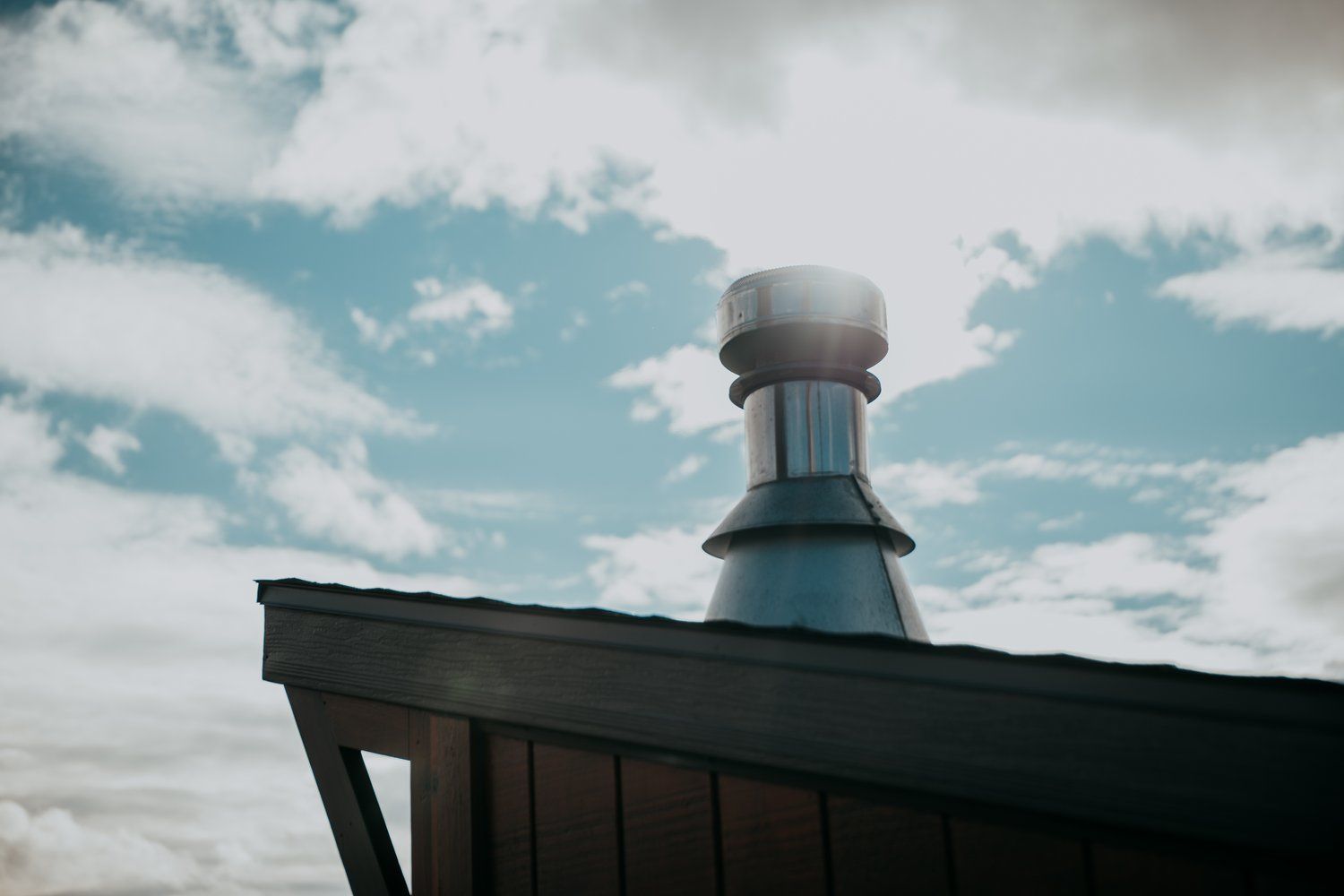A chimney on the roof of a building with a blue sky in the background.