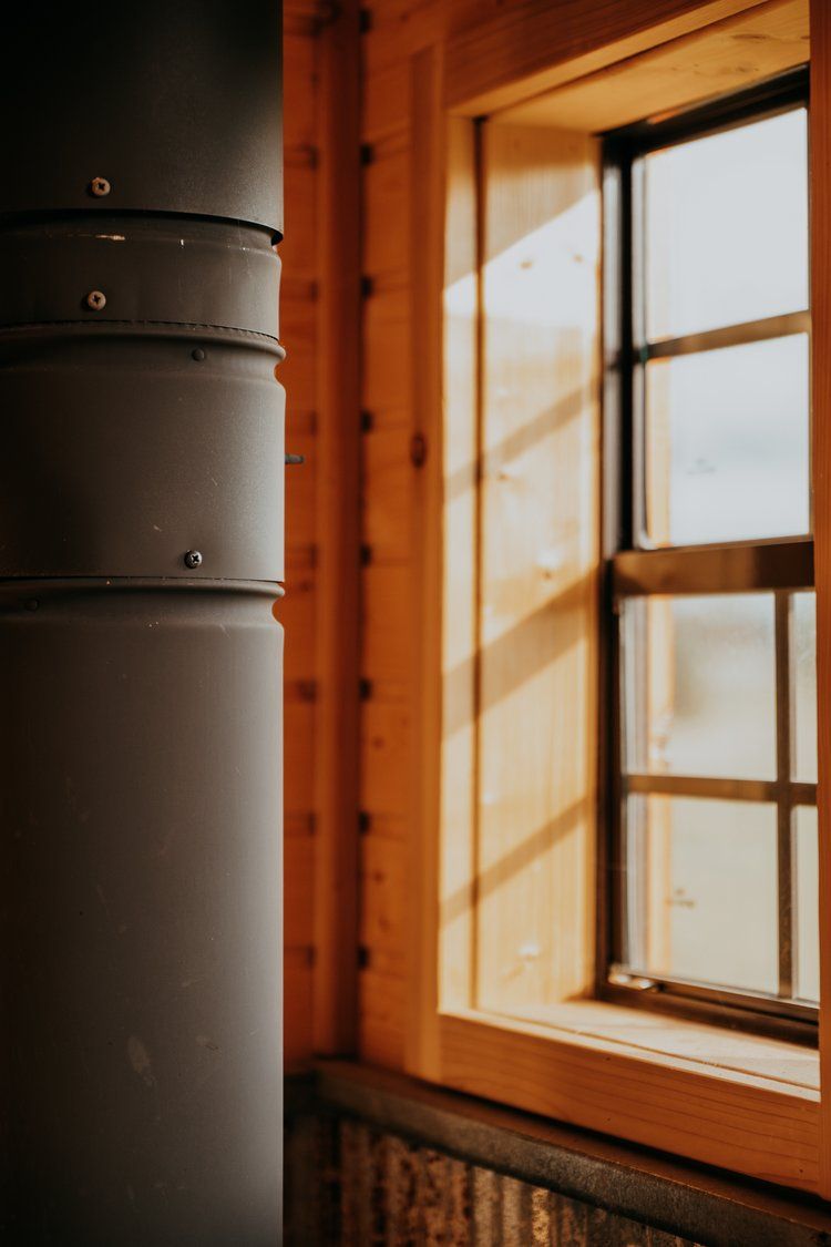 A window in a wooden house with a chimney in the corner.