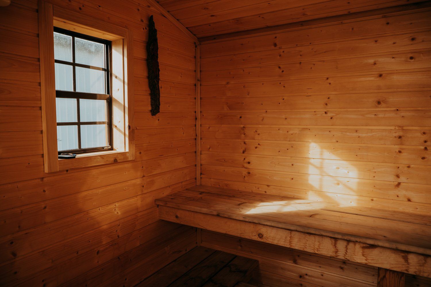 A wooden room with a window and a bench.