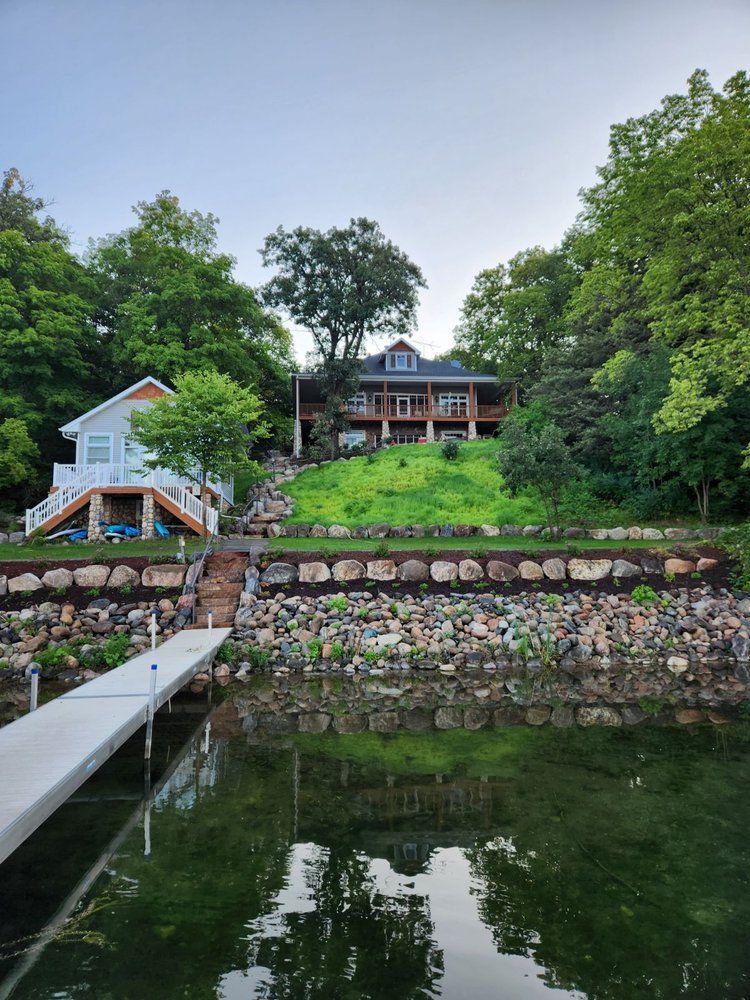 A large house is sitting on top of a hill next to a body of water.