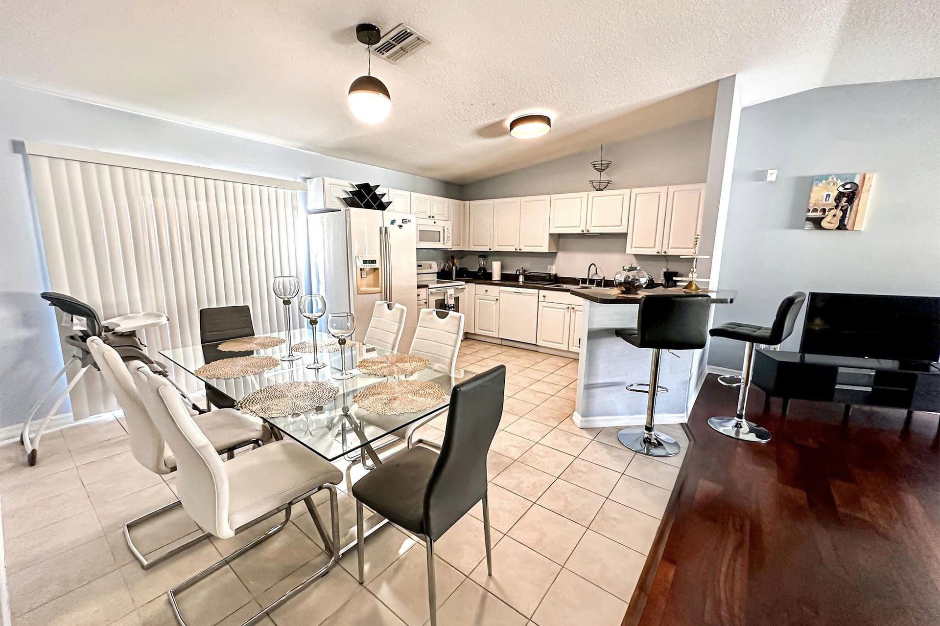 A dining room with a glass table and chairs and a kitchen.
