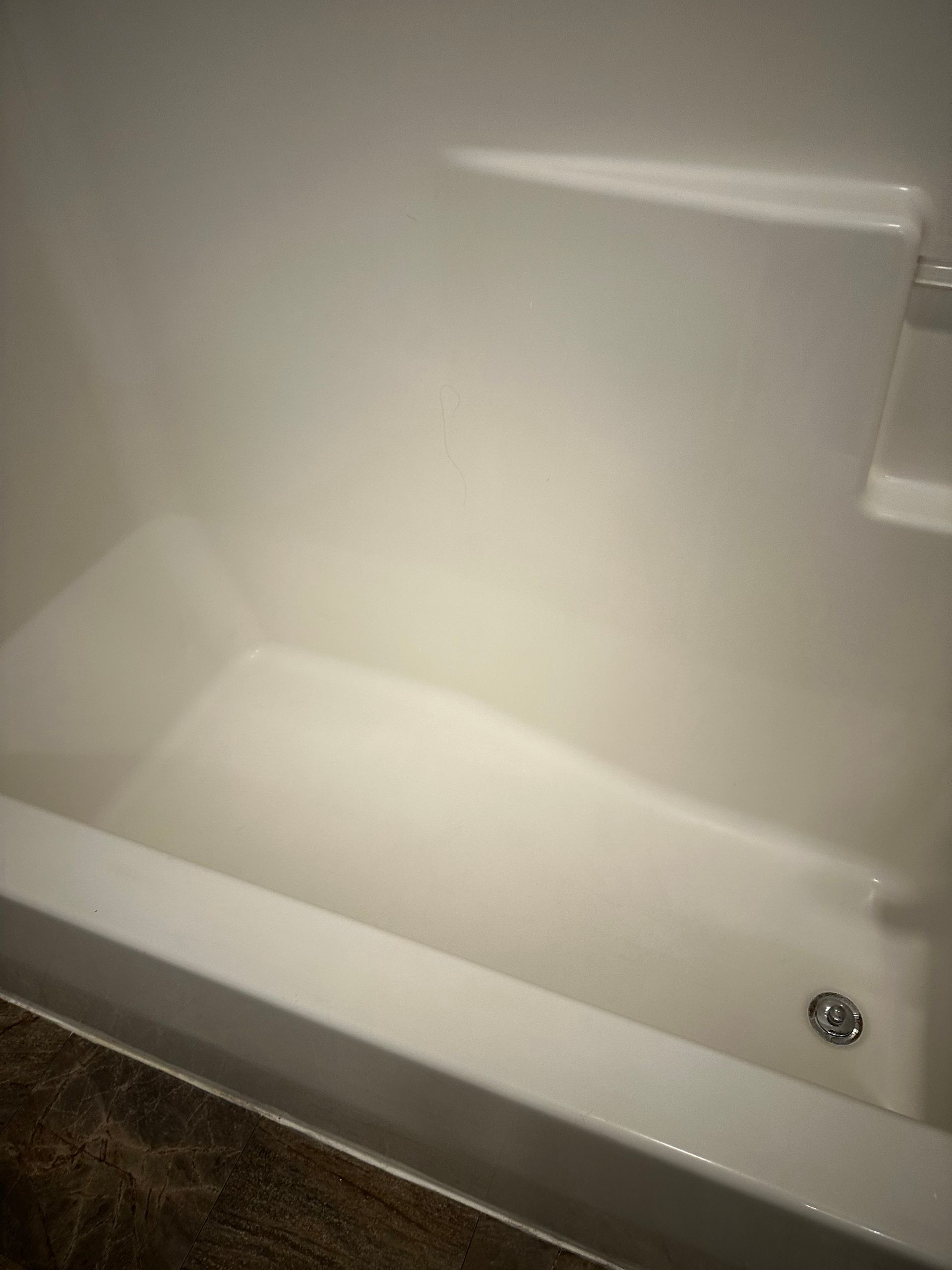 A white bathtub is sitting in a bathroom next to a wall.