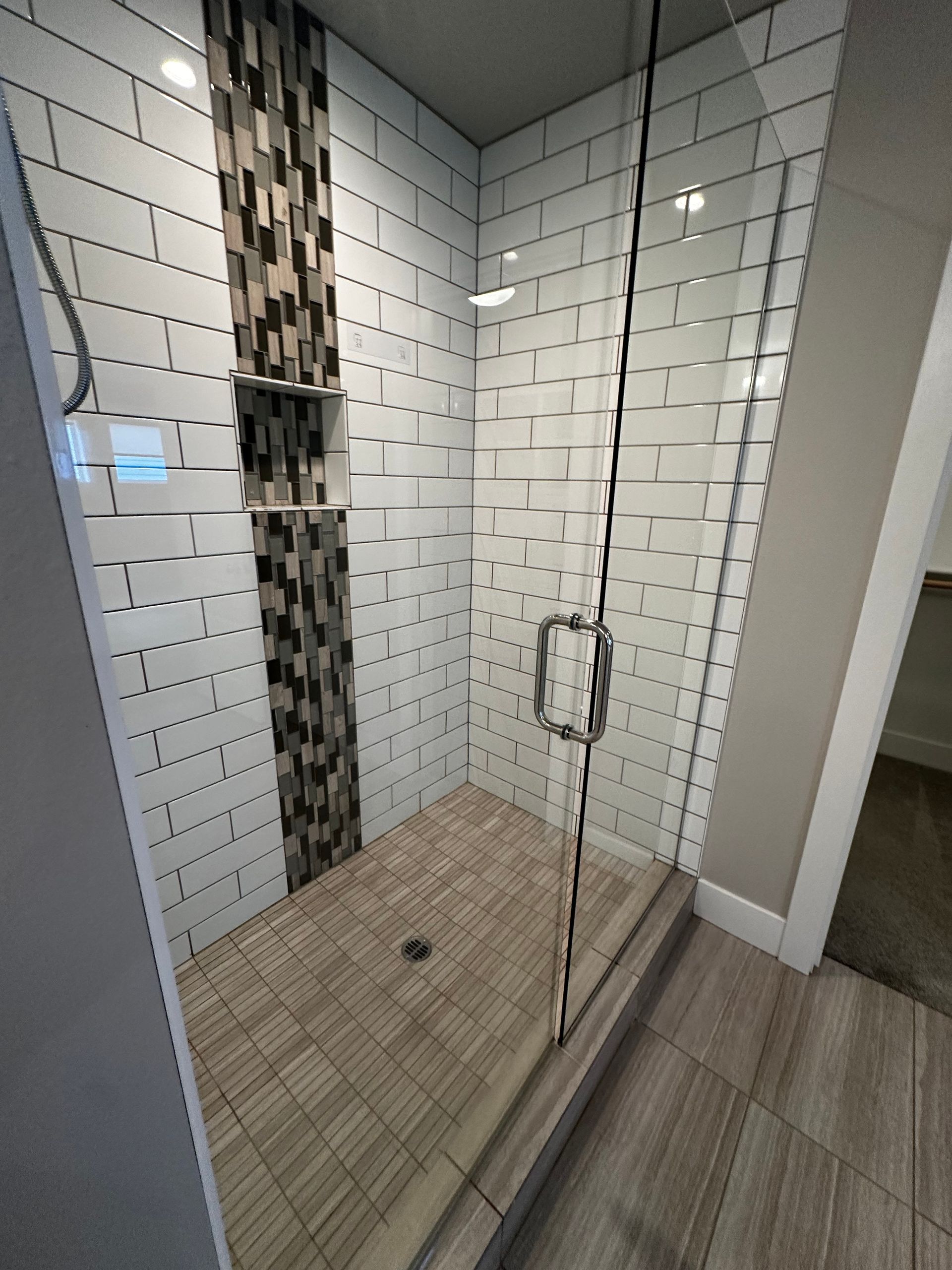 A bathroom with a walk in shower with a glass door