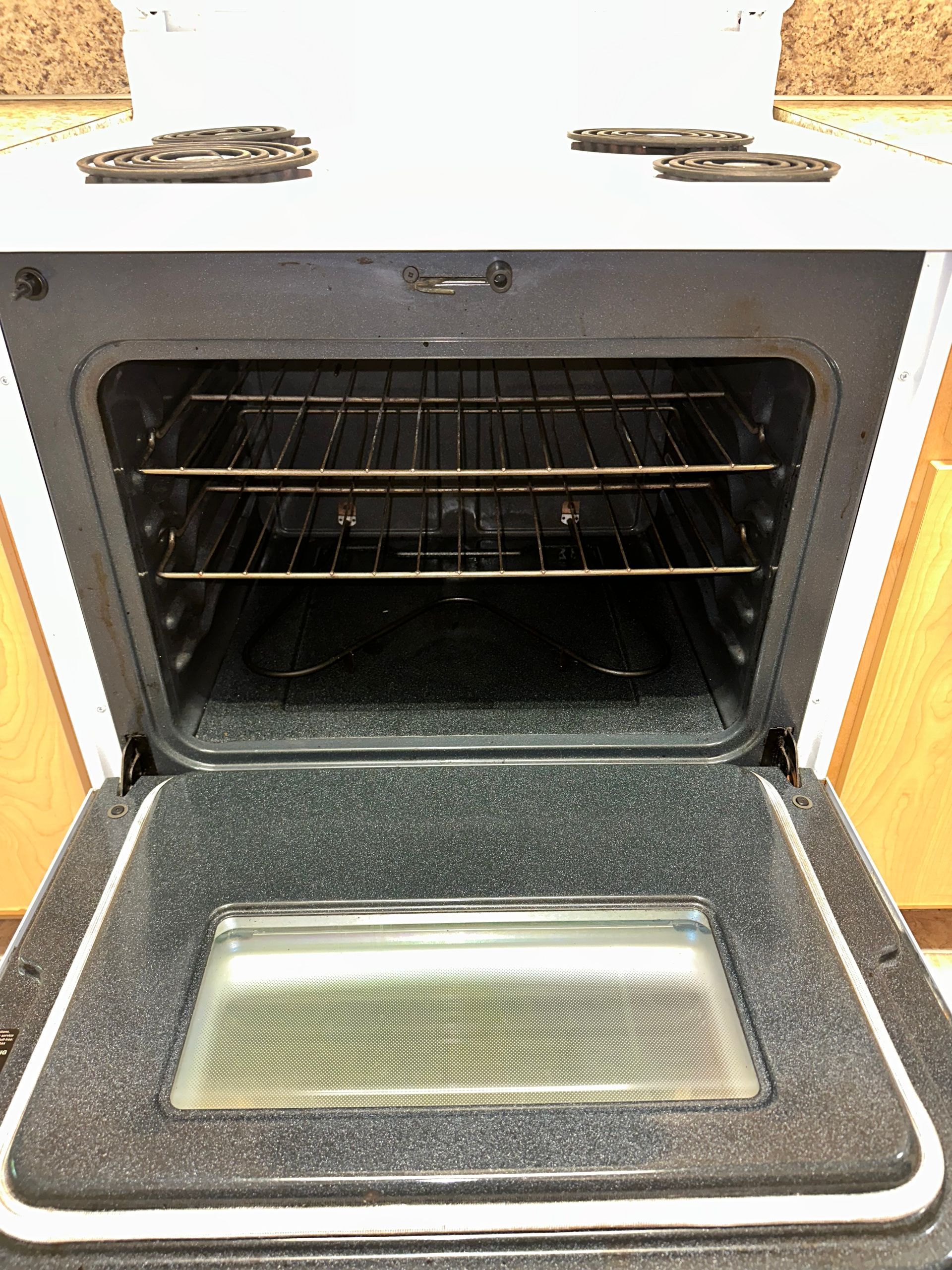 The inside of an oven with the door open and a tray in it.