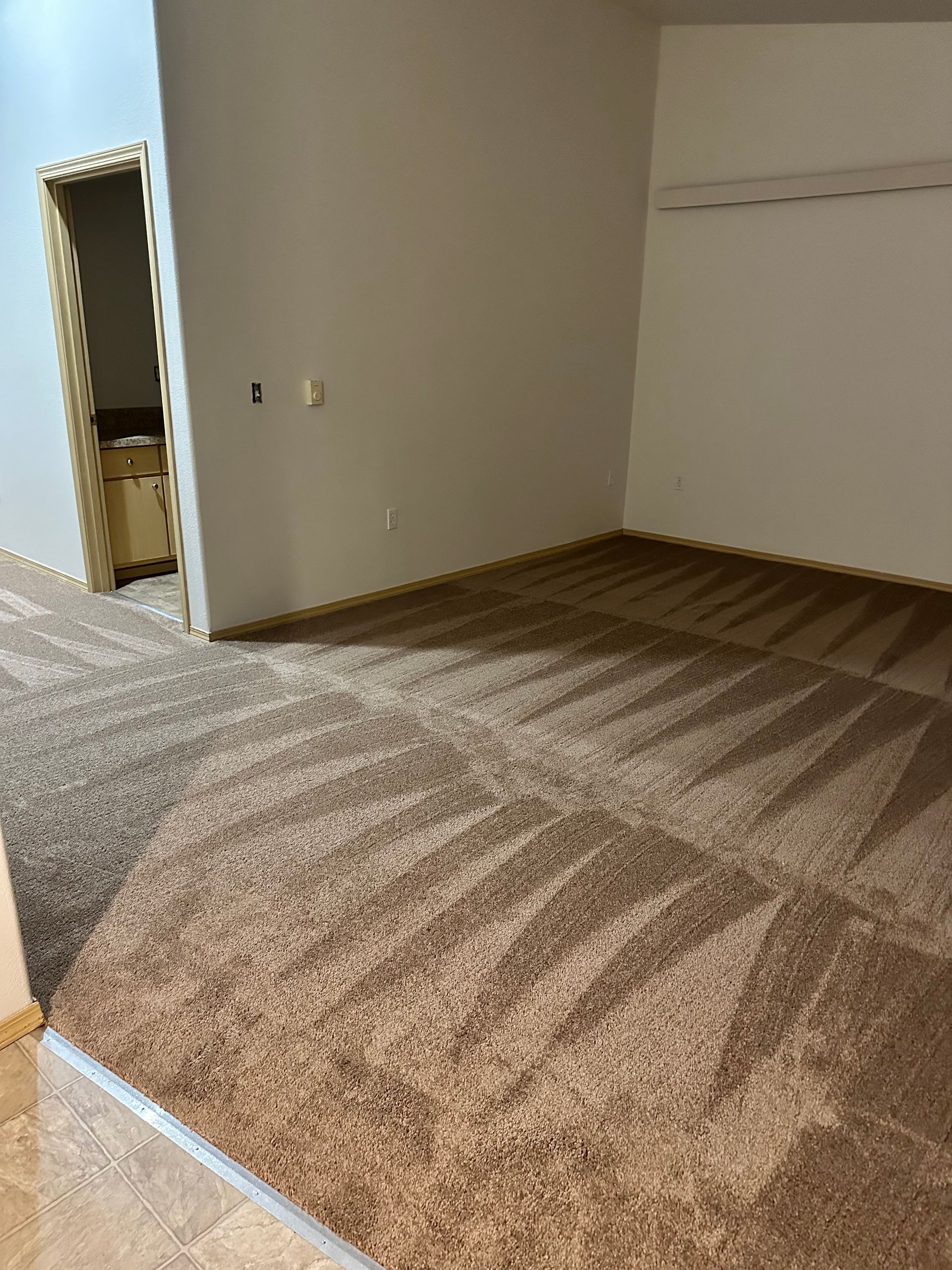 An empty room with a brown carpet and white walls.