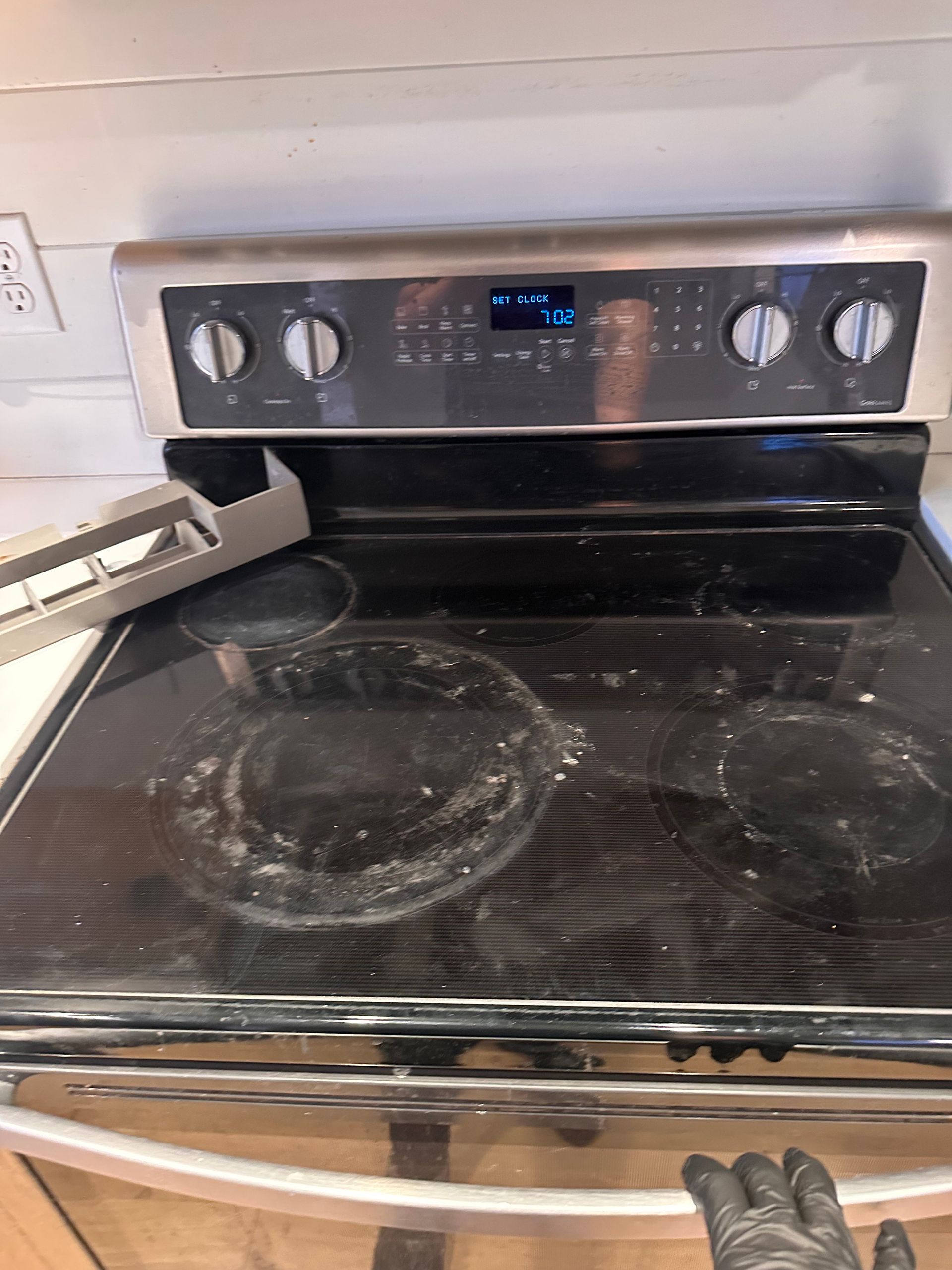 A person is cleaning a stove top oven in a kitchen.