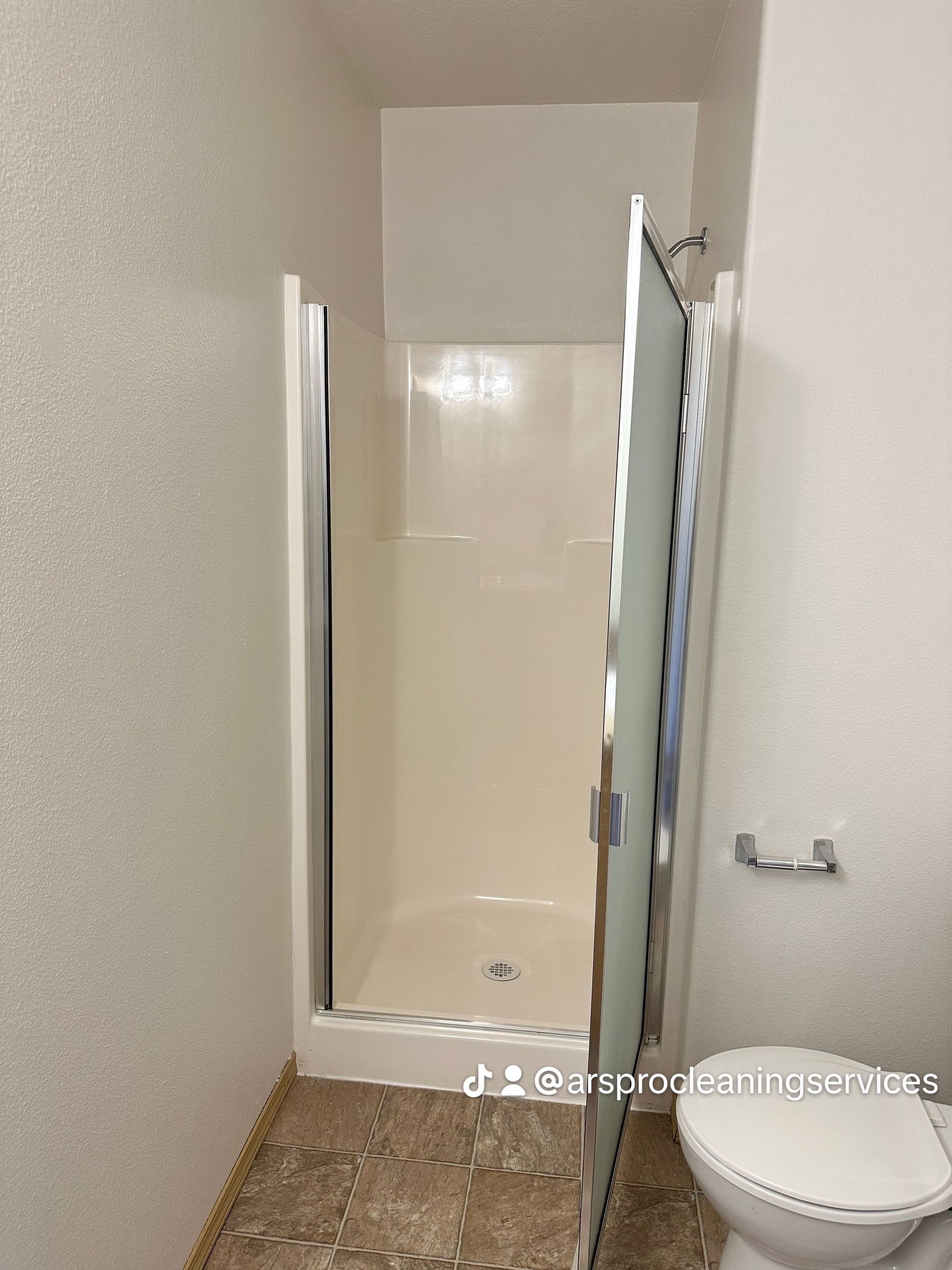 A bathroom with a toilet and a shower stall.