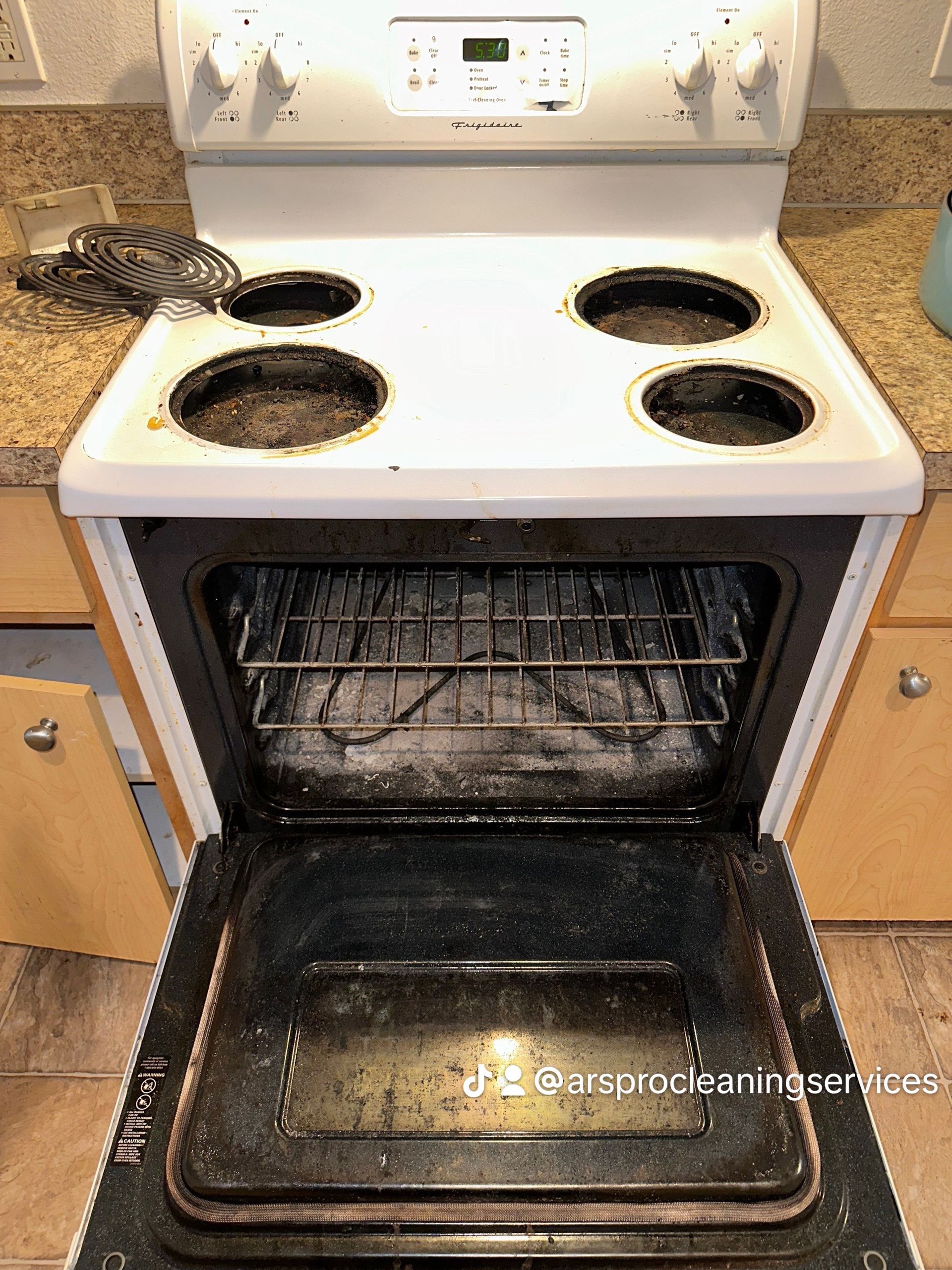 A dirty stove with the door open in a kitchen.