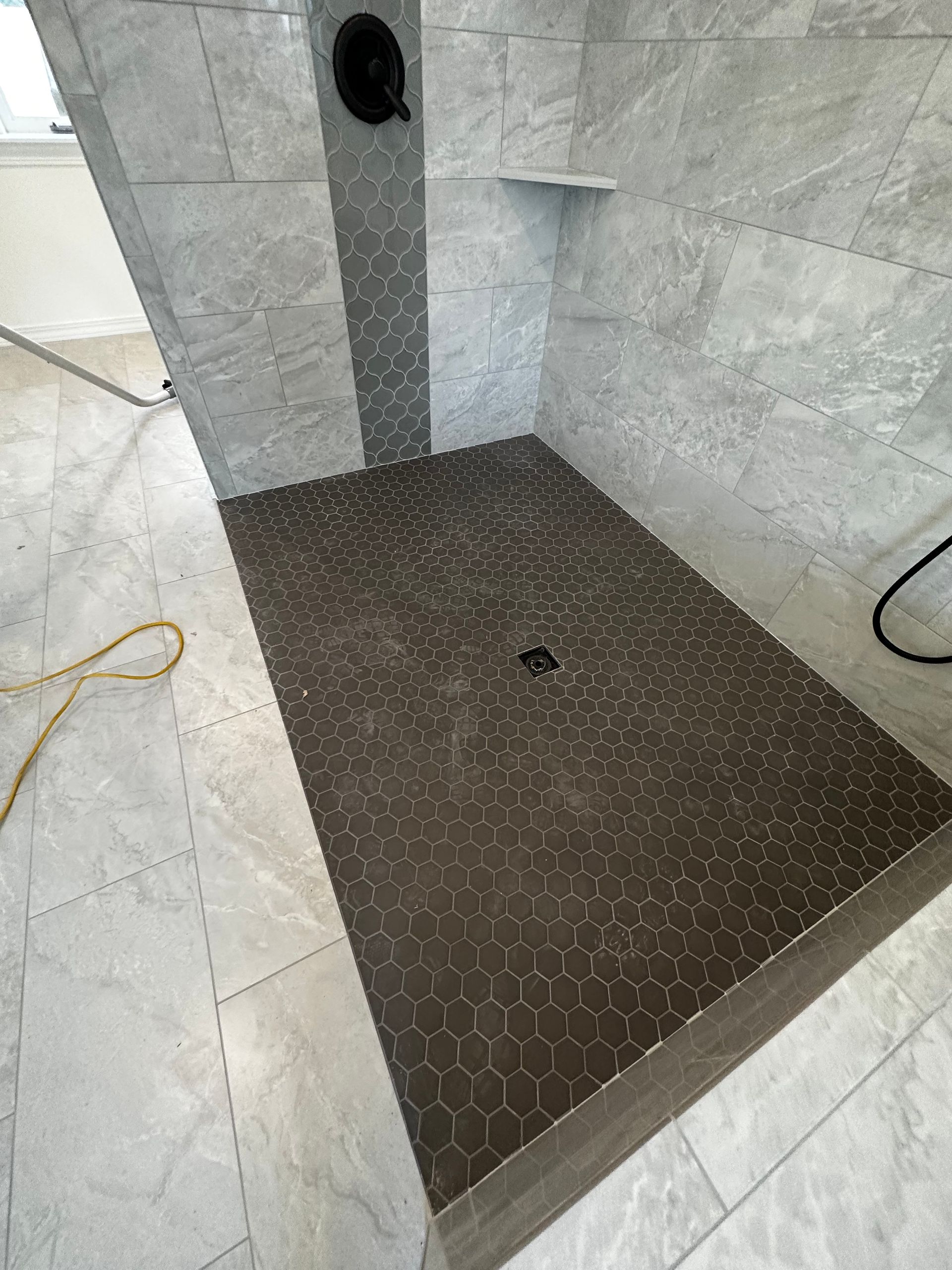 A walk in shower with a tiled floor and a shower head.