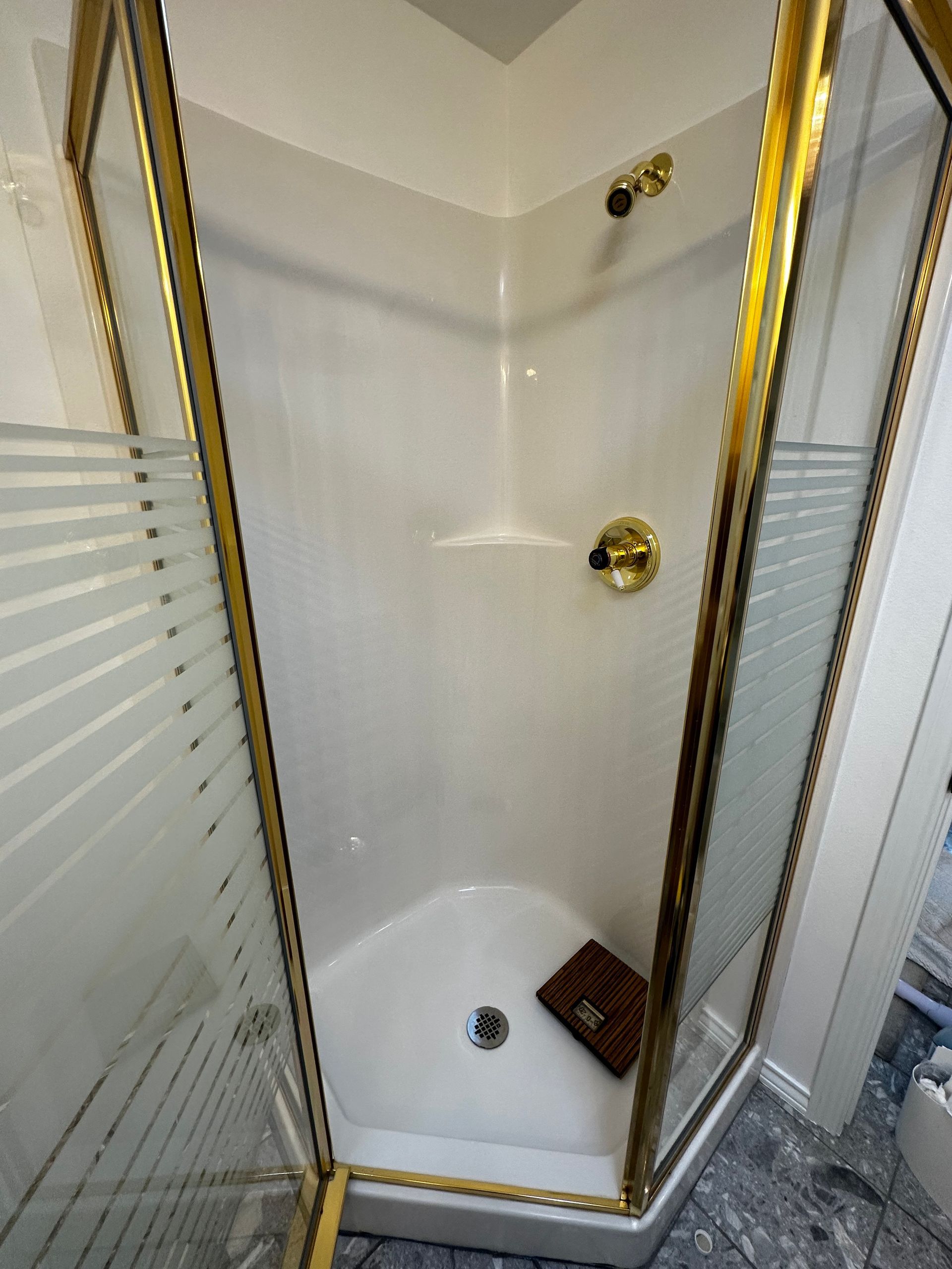 A bathroom with a shower stall with a gold frame