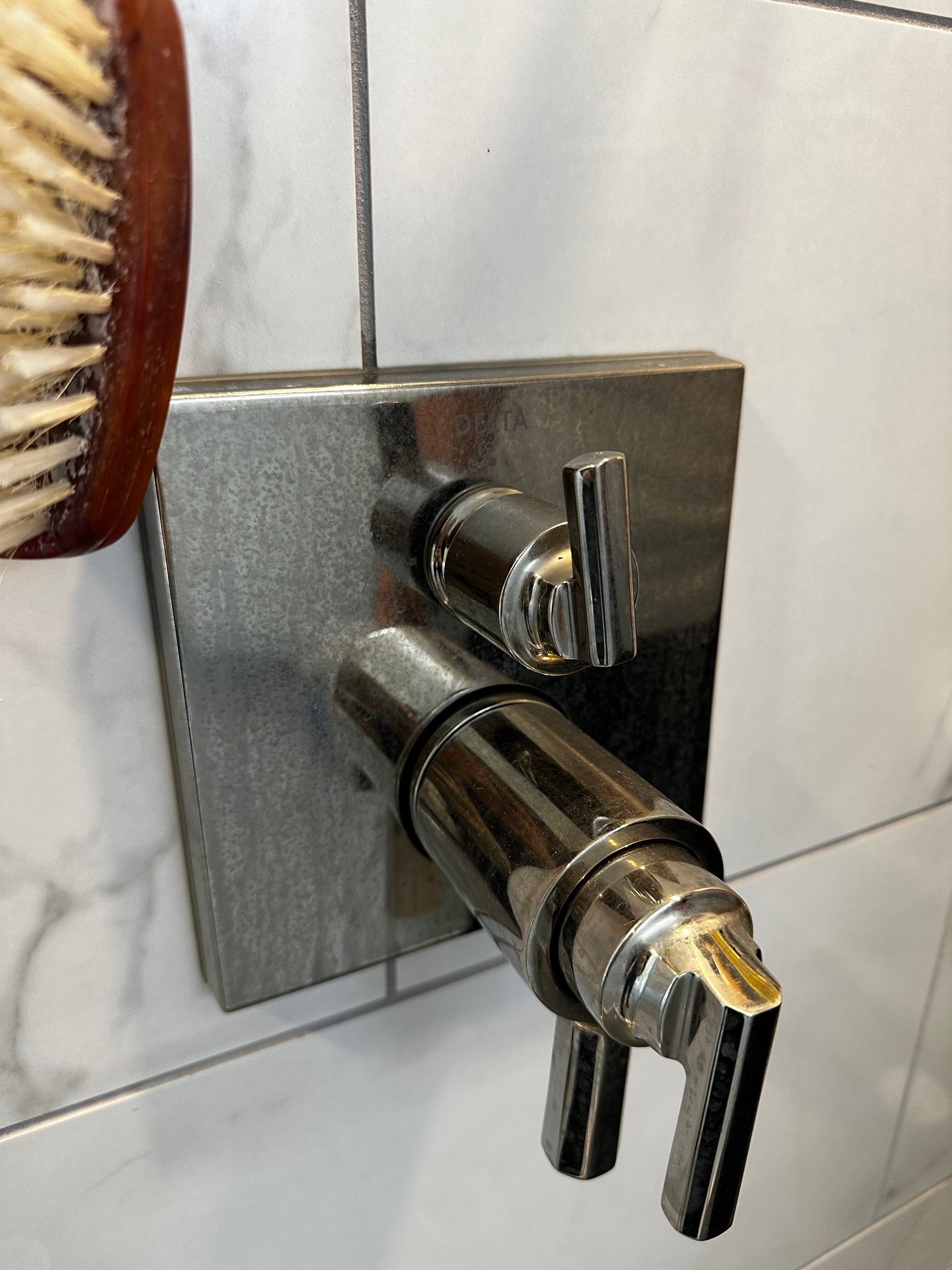 A shower head with a wooden brush next to it
