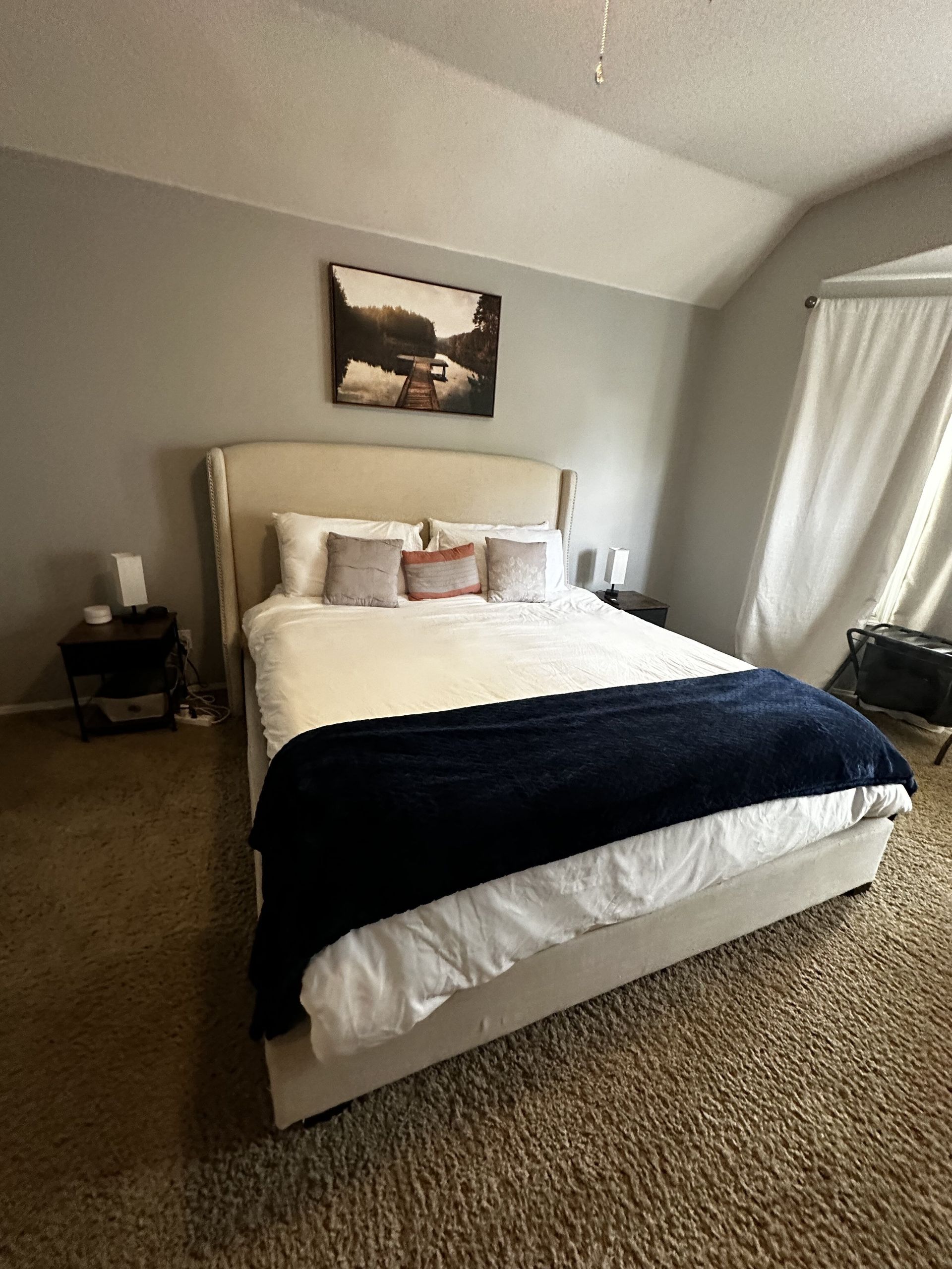 A bedroom with a large bed and a picture on the wall above it.