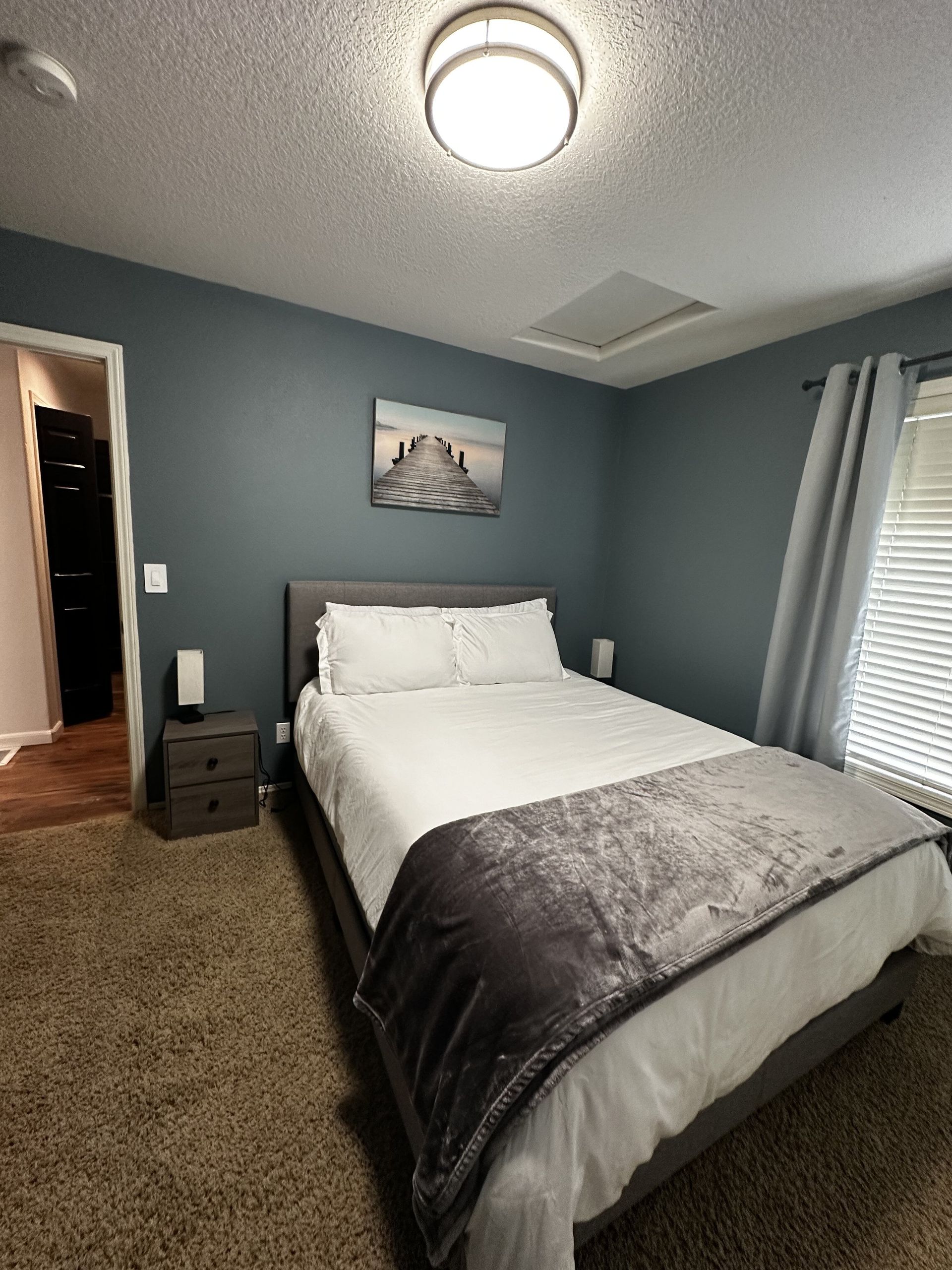 A bedroom with a bed , nightstand , and window.