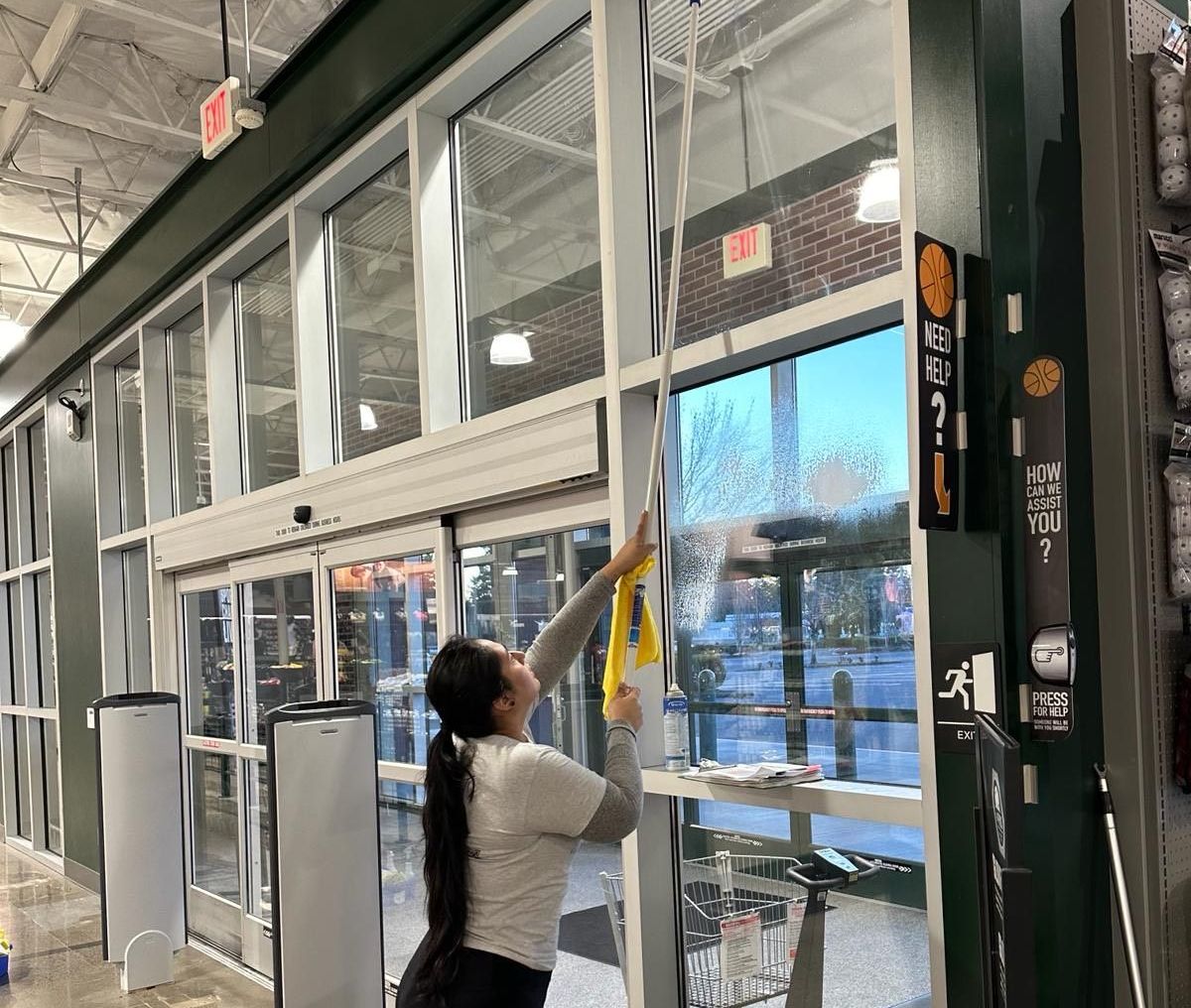 A woman is cleaning the windows of a store.