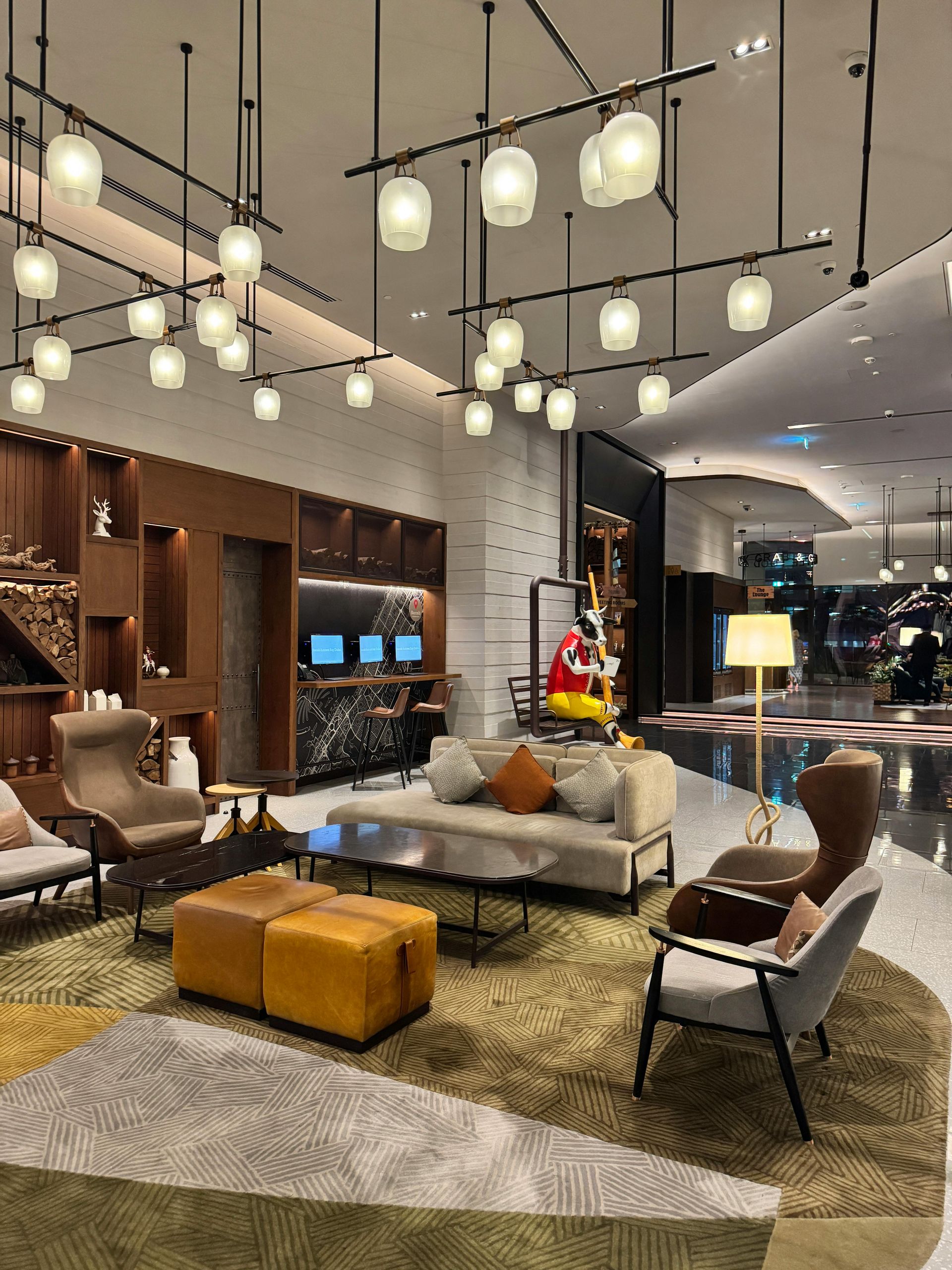 Modern hotel lobby with pendant lights, lounge chairs, sofas, and a central coffee table
