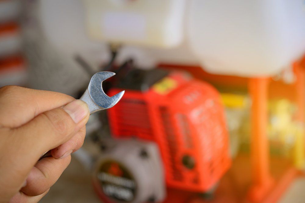 Une personne tient une clé devant une tondeuse à gazon.