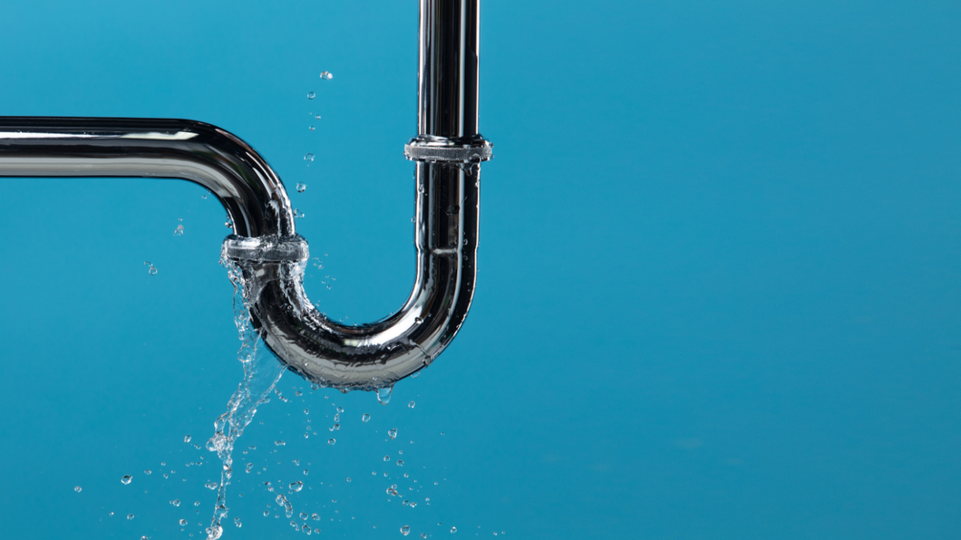Chrome faucet leaking water against a blue background