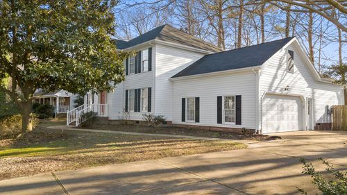 White two-story house with black shutters, attached garage, and a driveway.