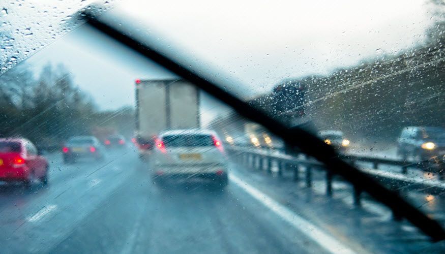 A car is driving down a highway in the rain. | Import Specialty Service