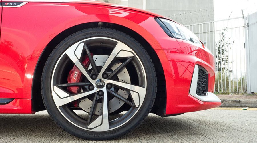 A close up of a red car 's front wheel and brake caliper. | Import Specialty Service