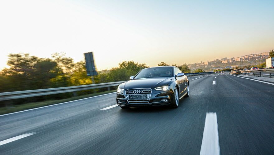 A car is driving down a highway at sunset. | Import Specialty Service