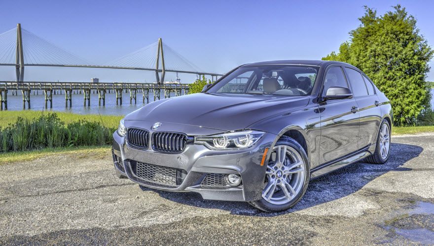 A bmw 3 series is parked on the side of the road in front of a bridge. | Import Specialty Service