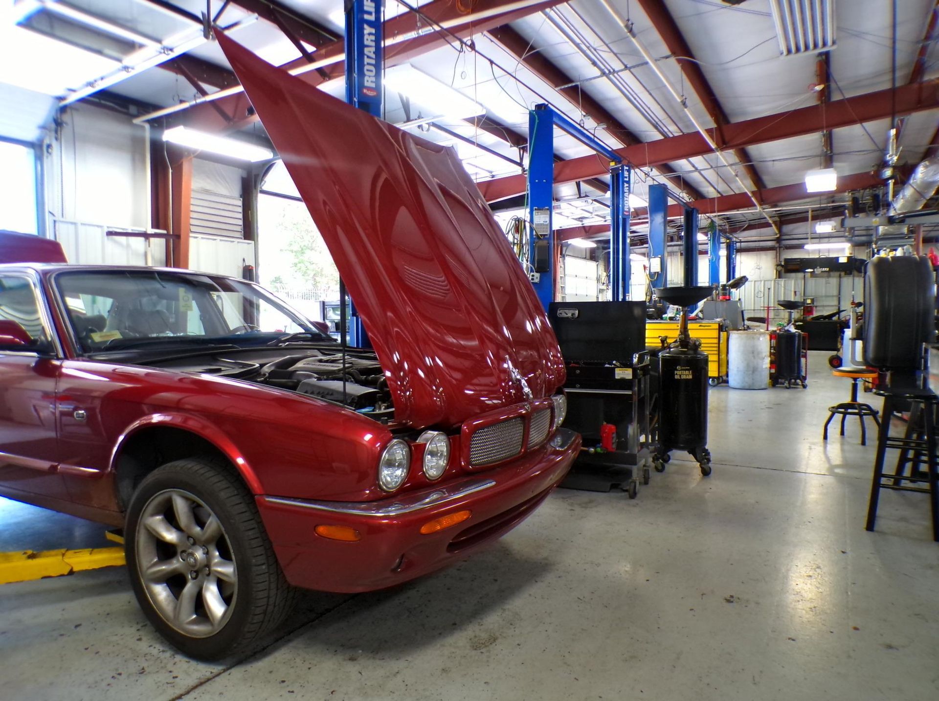 A red car with the hood up in a garage | Import Specialty Service