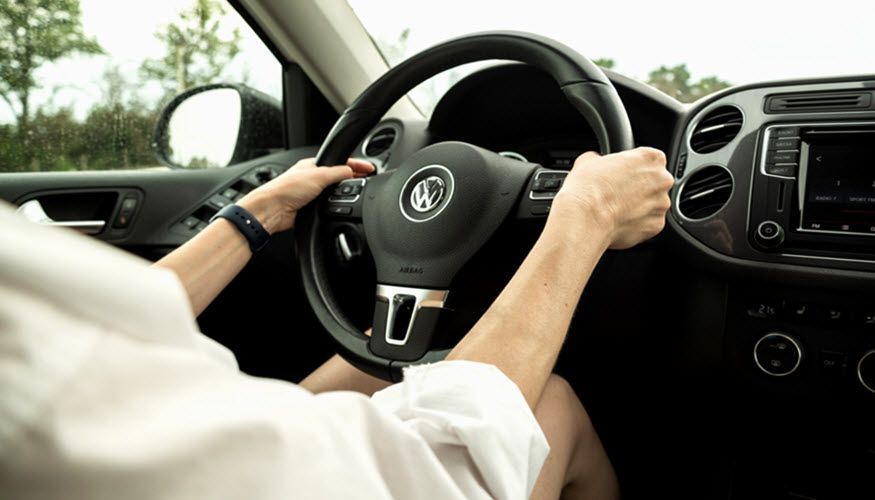 A person is driving a car with their hands on the steering wheel. | Import Specialty Service
