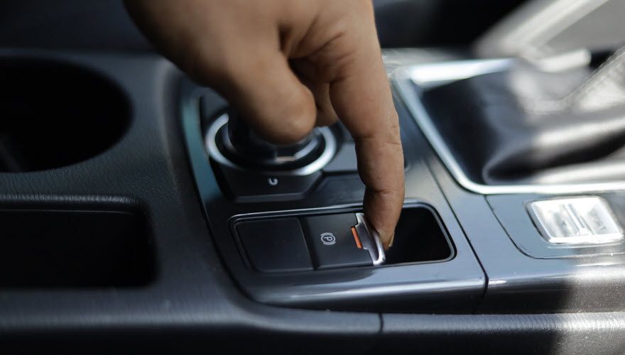 A person is pressing a button on the dashboard of a car. | Import Specialty Service