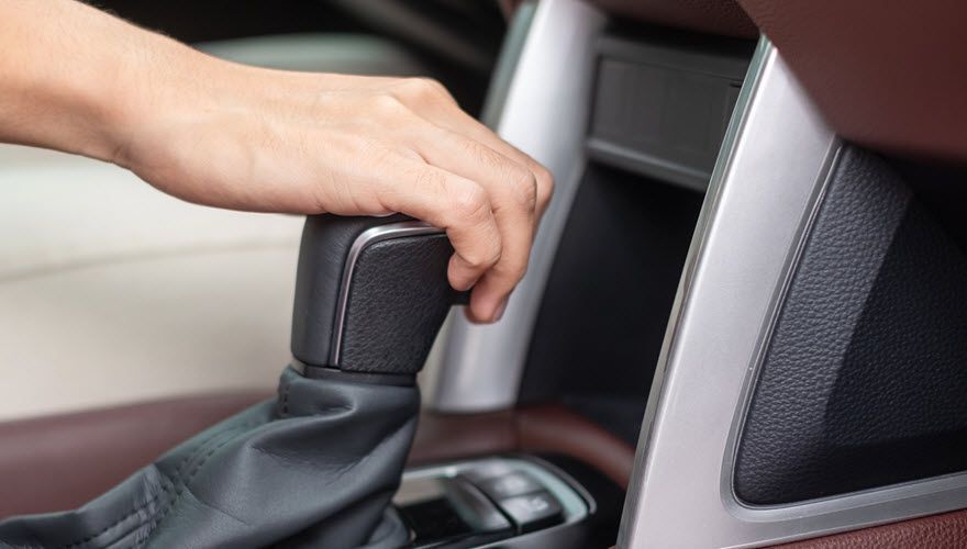 A person is changing gears in a car. | Import Specialty Service